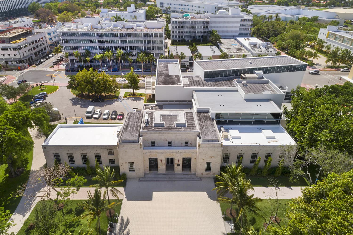 Aerial view of a contemporary institutional building with cream stone facades, geometric massing, and integrated landscaping surrounded by trees and modern campus structures by David Gauld Architect.