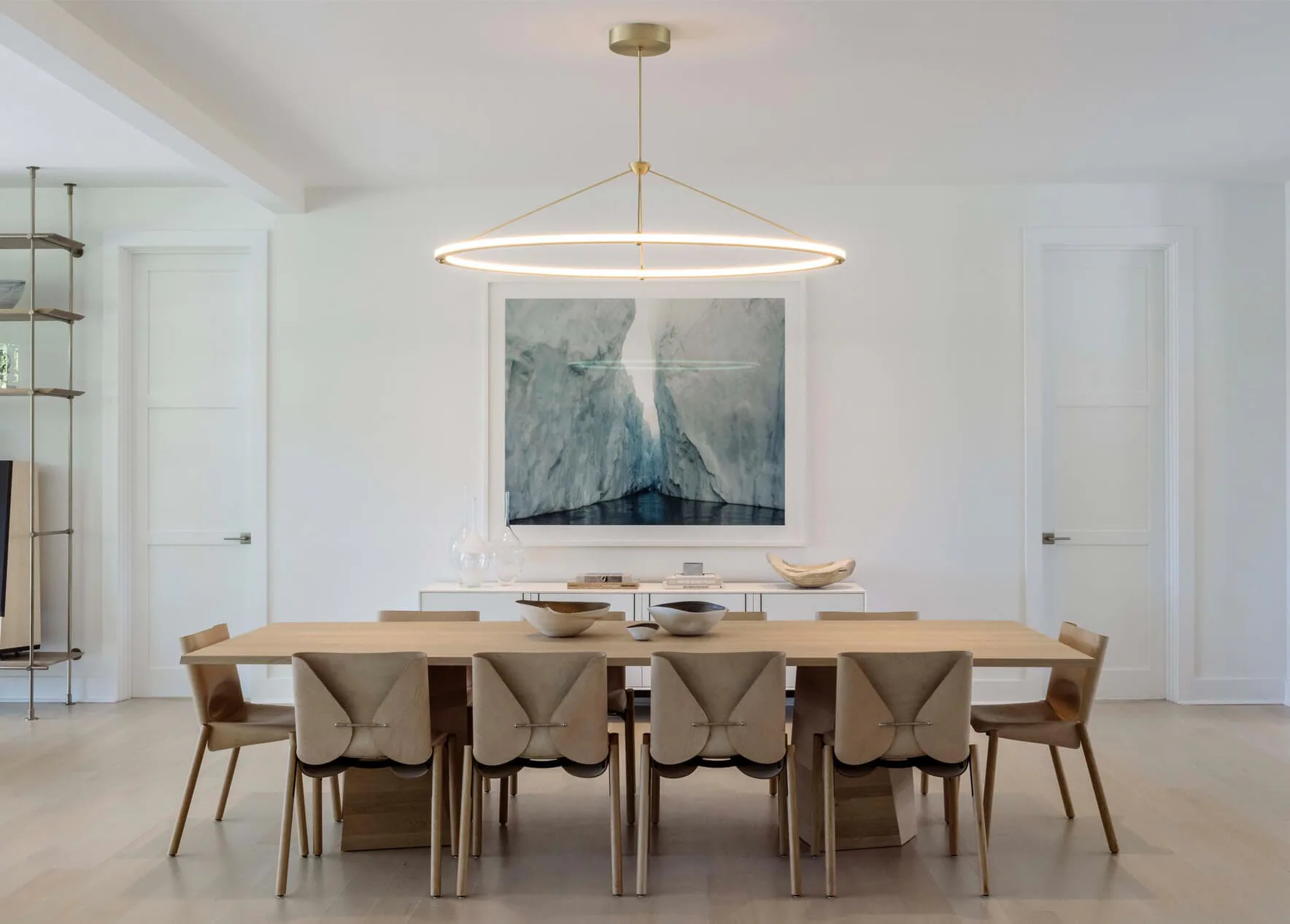 Modern dining room with light wood table, woven chairs, and circular pendant light featuring marble artwork above, designed by DHD Architecture & Interior Design.