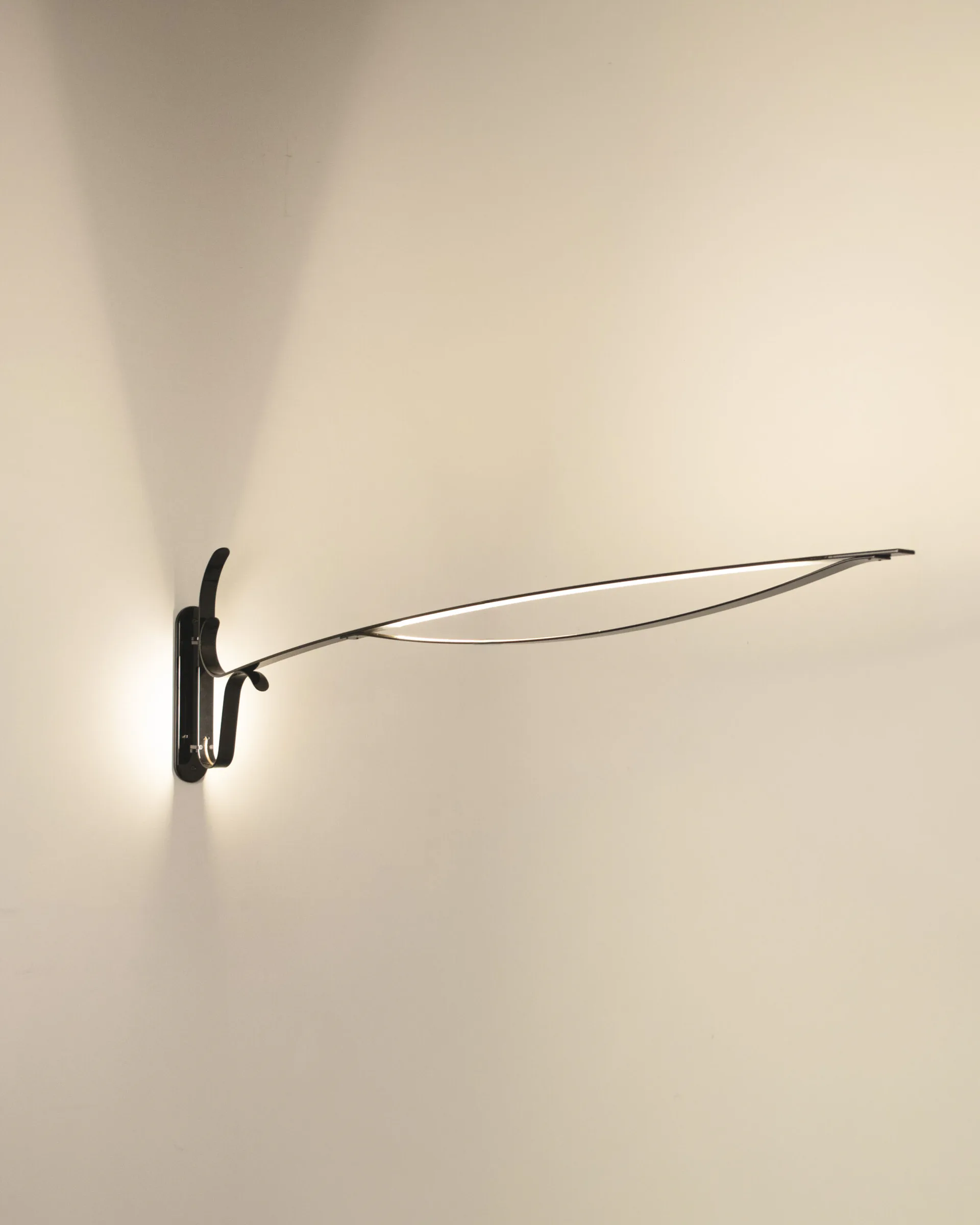 Minimalist black wall-mounted sculptural light fixture with curved linear arms extending horizontally against a cream wall by David Weeks Studio.