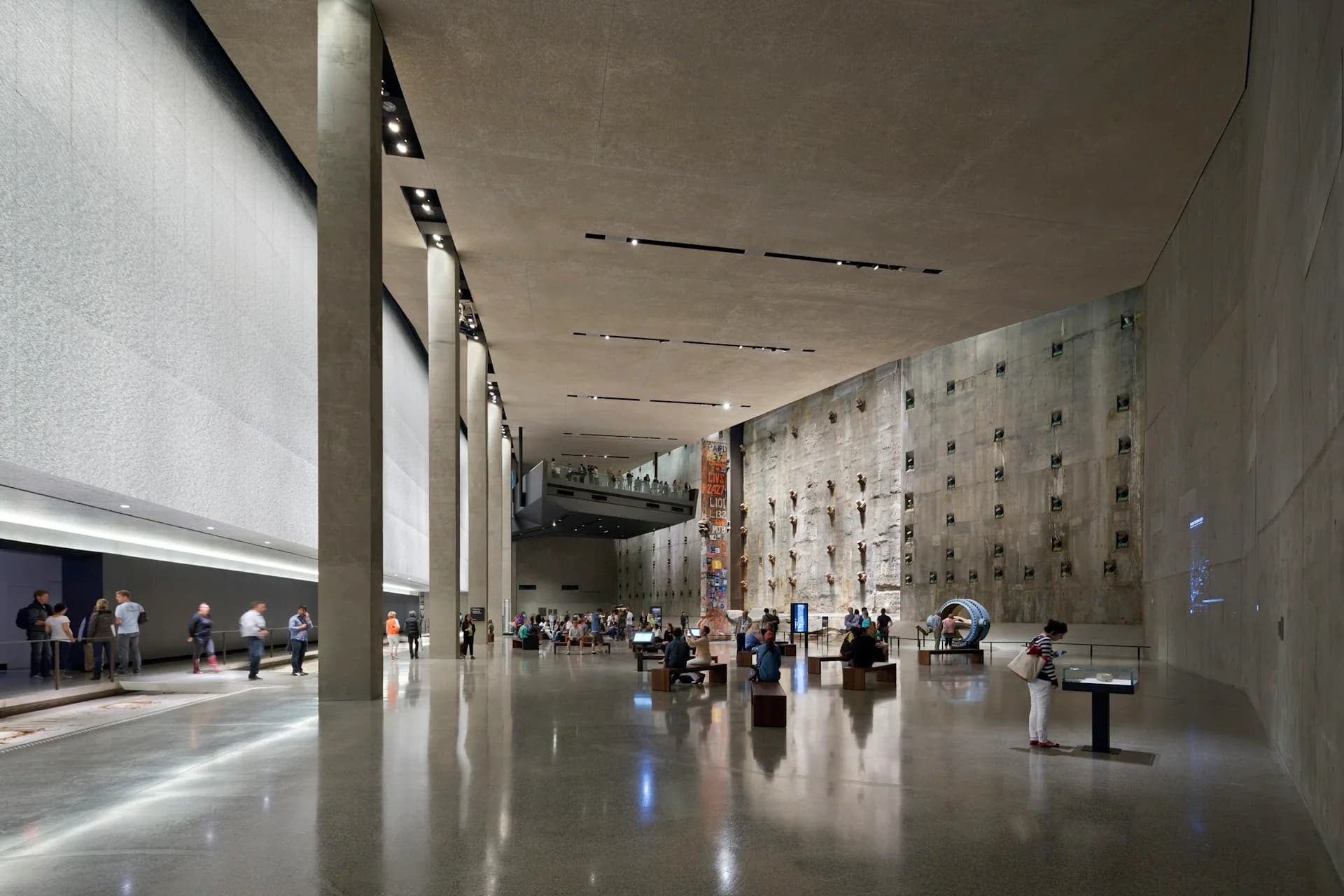 Expansive museum lobby with polished concrete floors, soaring white walls, linear ceiling lights, and integrated acoustic paneling, designed by Davis Brody Bond, a Page Company.