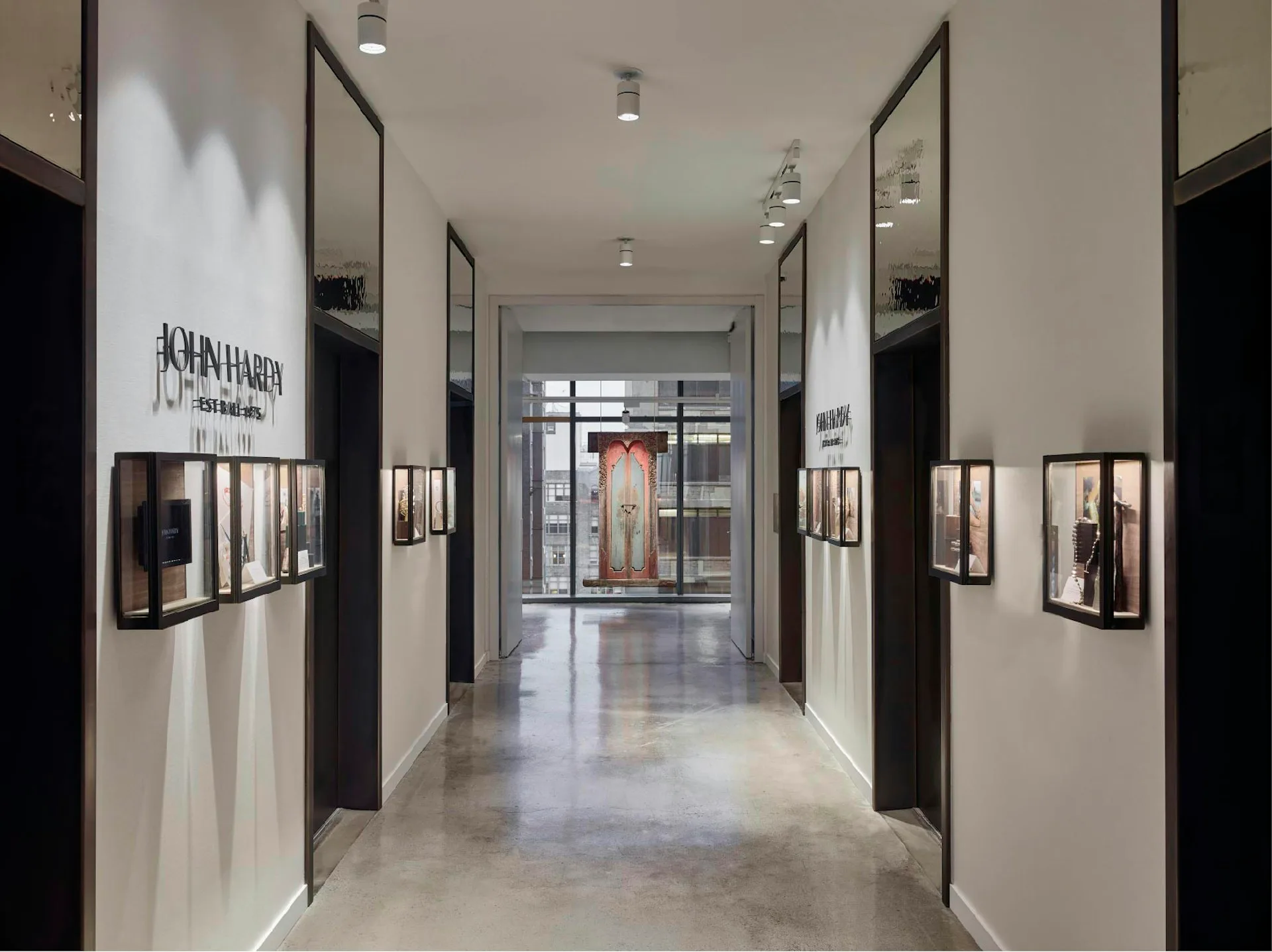 Modern gallery corridor with polished concrete floors, black-framed glass partitions, white walls, and framed artwork displays by Design Republic.