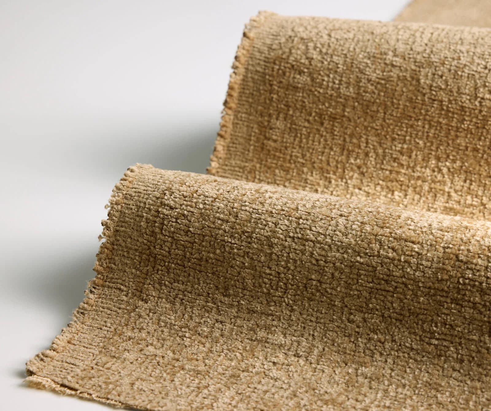 Close-up detail of a textured woven fabric in neutral beige tones showing the material's dimensional weave structure by Designtex.