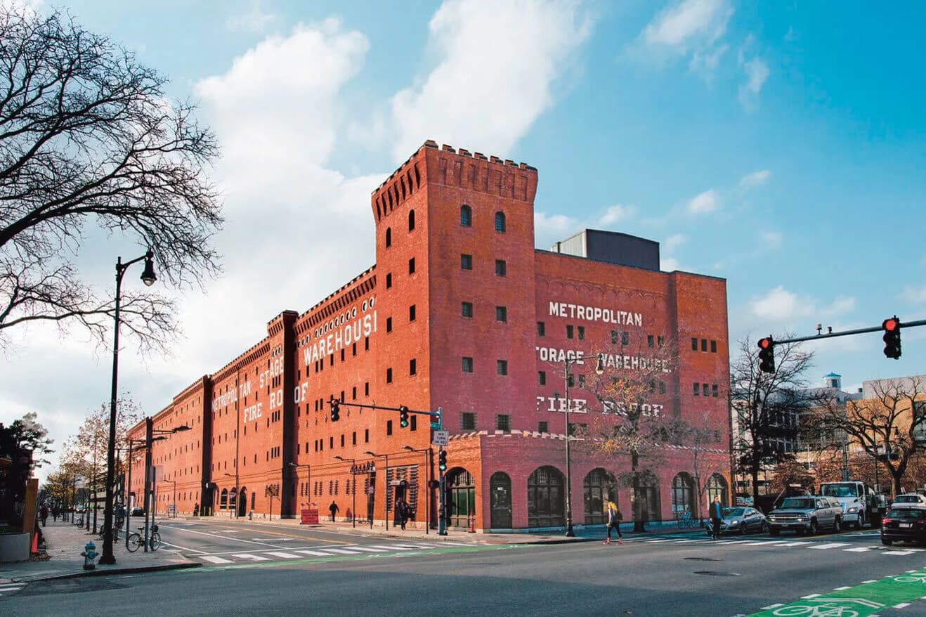 Red brick metropolitan building with distinctive tower and signage on urban corner street, architectural work by Diller Scofidio + Renfro.