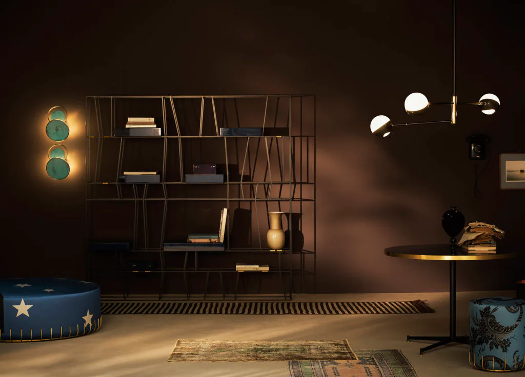 Dark contemporary interior with geometric wall installation, turquoise pendant lights, styled shelving, and sculptural furniture pieces by Dimoremilano.