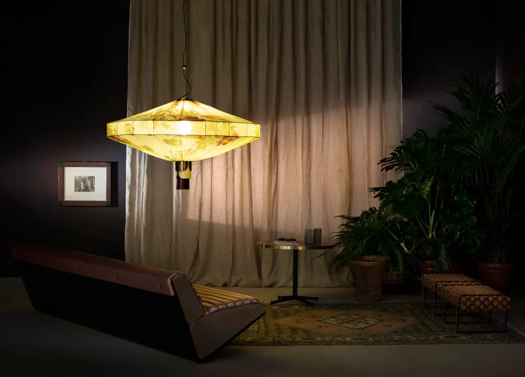 Minimalist interior with geometric yellow pendant light, neutral curtains, potted plants, and wood furniture by Dimoremilano.