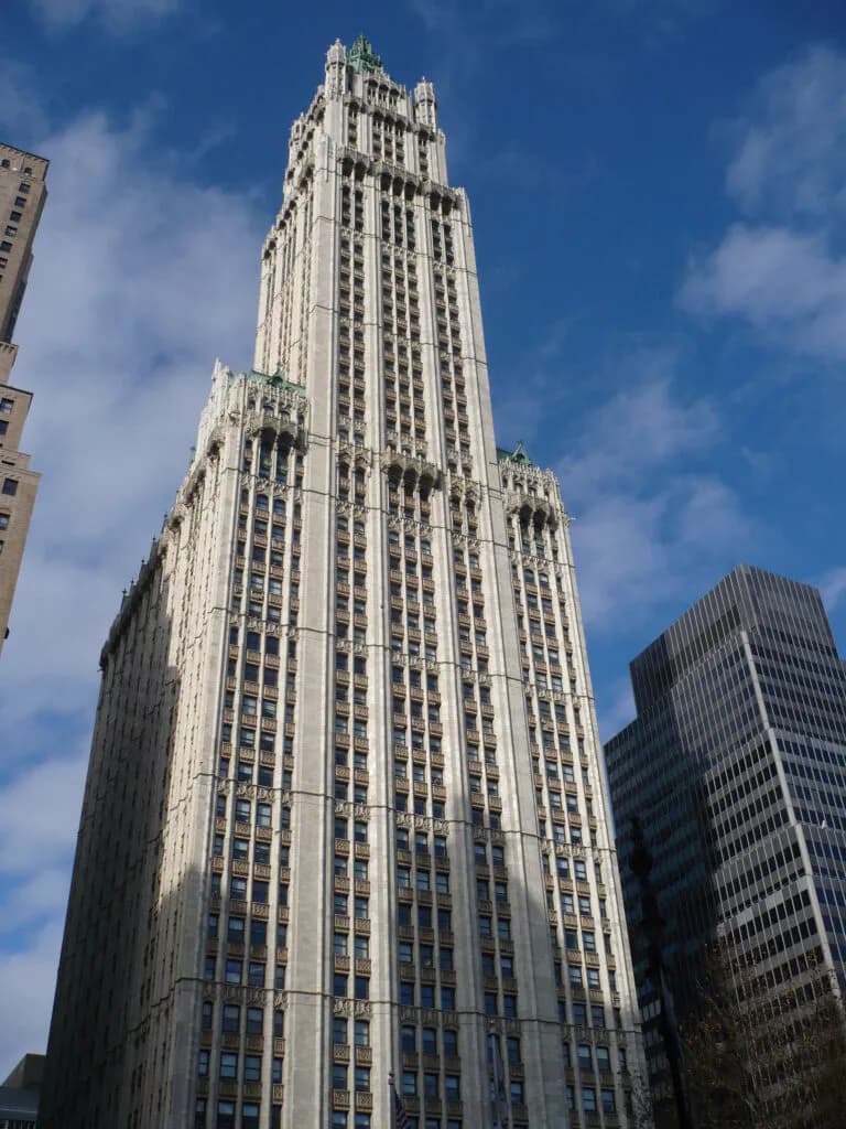 Tall Art Deco skyscraper with white limestone facade and ornate crown, photographed against blue sky among other Manhattan buildings by DJ Associates Architect, pc