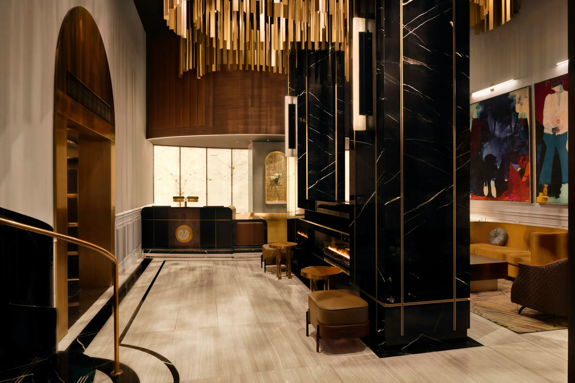 Modern hotel lobby featuring black marble columns, brass pendant lighting, warm wood accents, and minimalist furnishings designed by DLR Group.