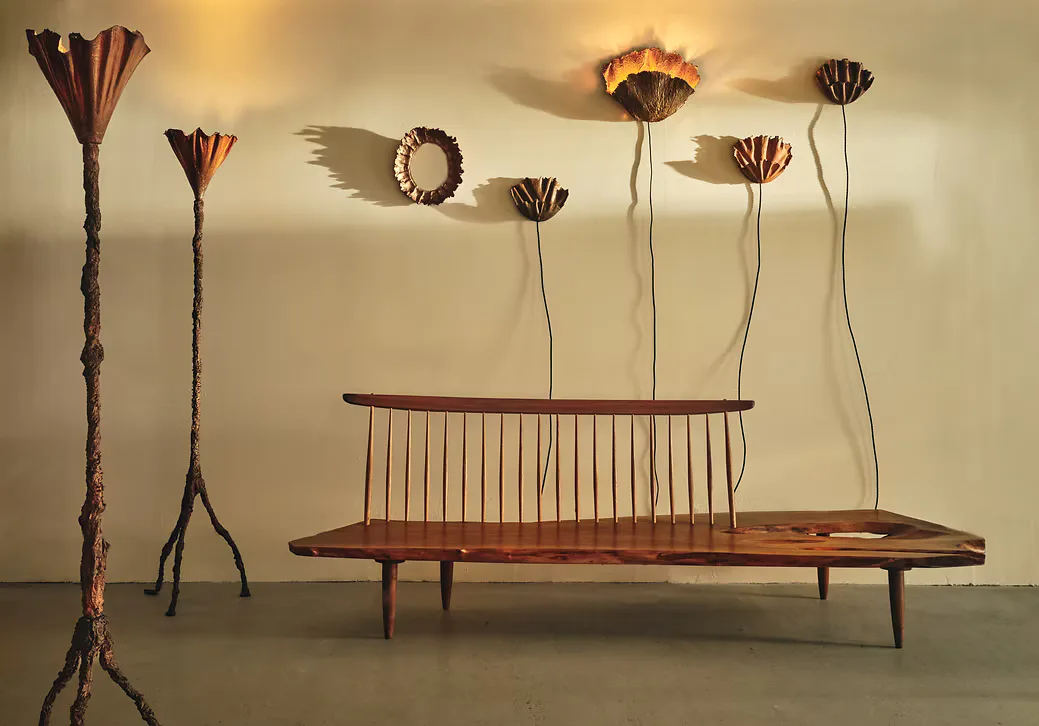 Mid-century modern furniture installation featuring a wooden bench with spindle back and tall sculptural floor lamps with organic forms in warm wood tones by Dobrinka Salzman Gallery.