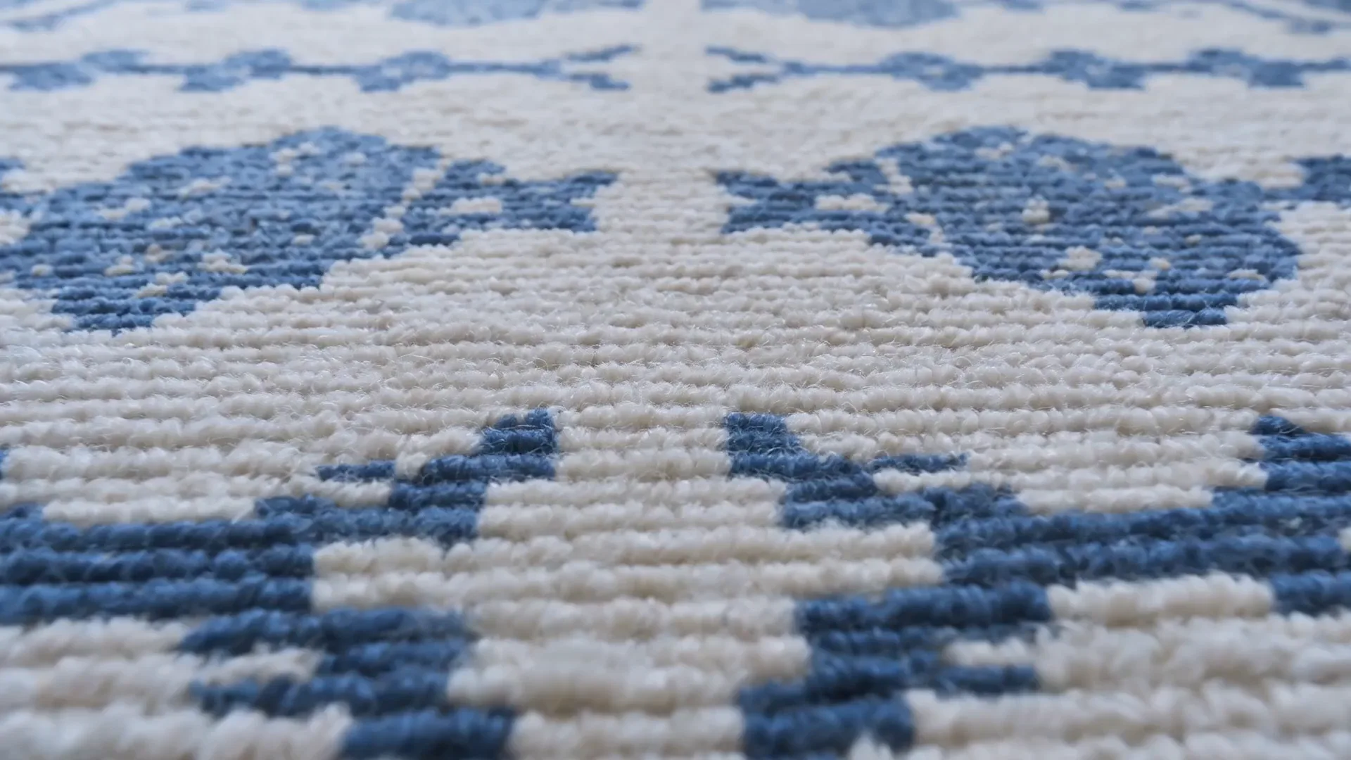 Close-up detail of a geometric patterned area rug in blue and cream tones featuring repeating diamond motifs, by Doris Leslie Blau.