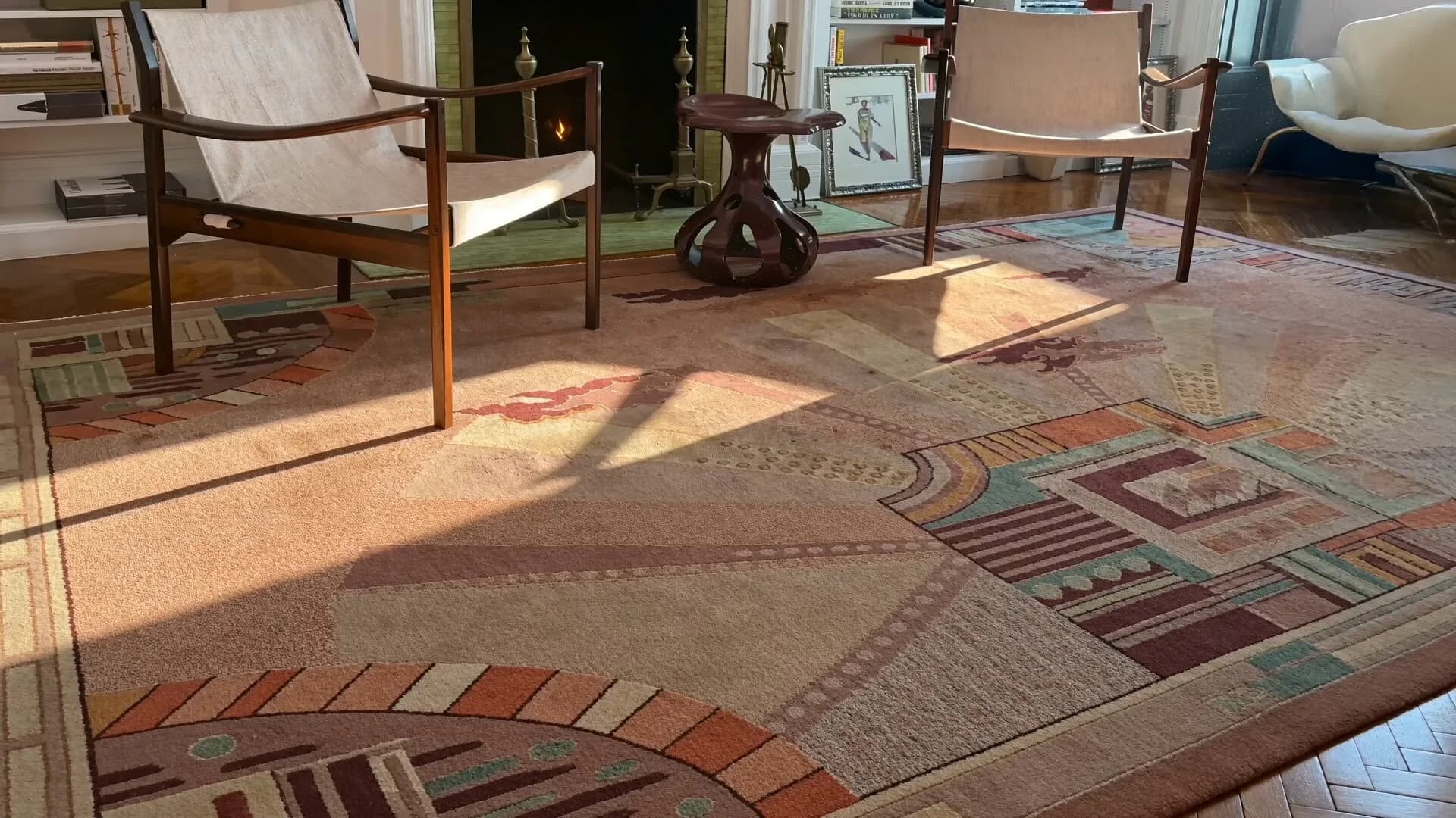 Sunlit interior showroom featuring an intricate geometric patterned area rug in warm earth tones with burgundy and rust accents, modern furniture silhouettes, and refined spatial design by Doris Leslie Blau.