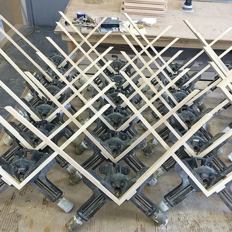 Overhead view of white lattice-frame architectural installations with integrated mechanical components arranged diagonally on concrete floor by Downing Frames.