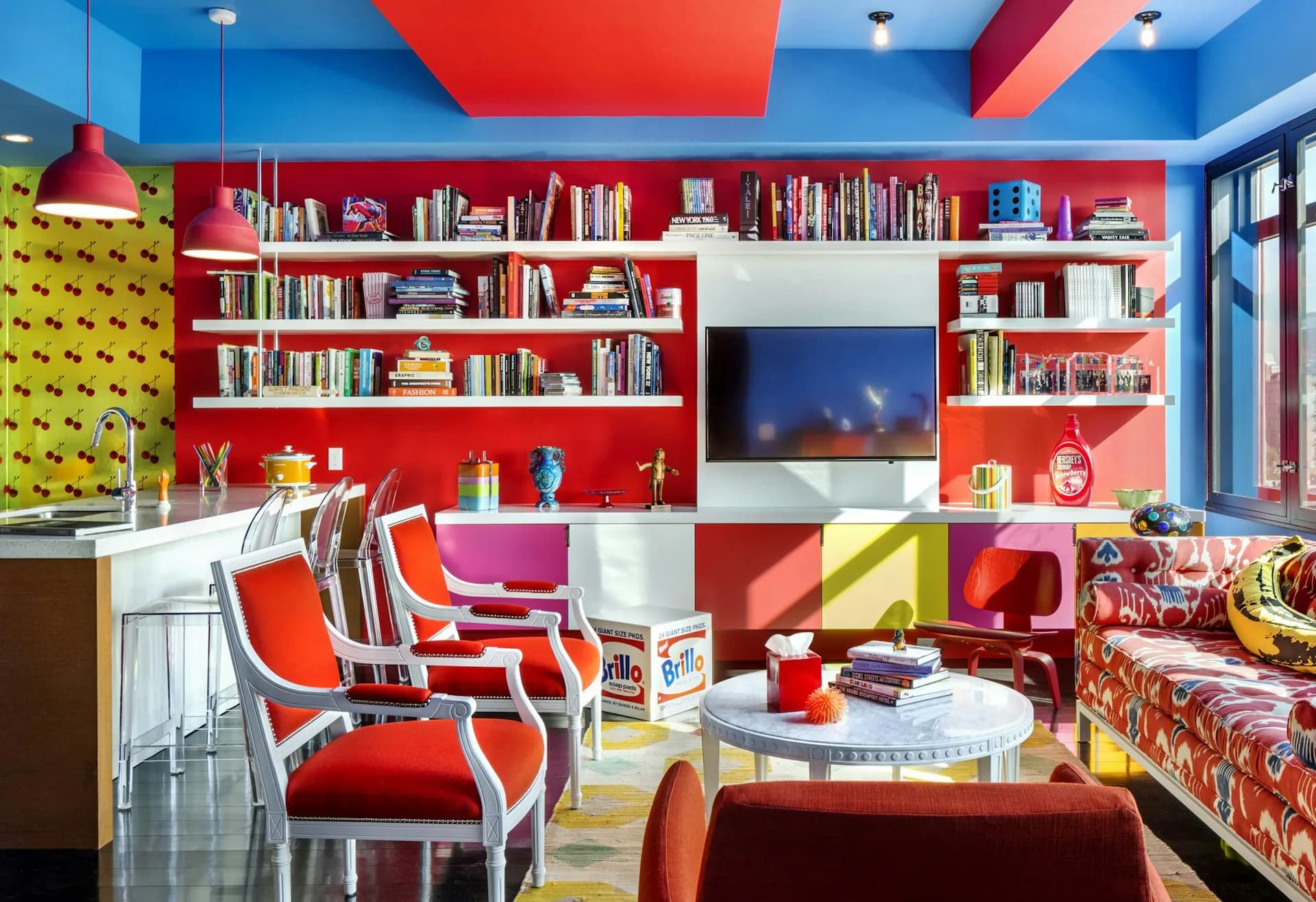 Vibrant playroom with red shelving, blue ceiling, bold geometric patterns, and colorful furniture by Ed Kopel, Architect, P.C.