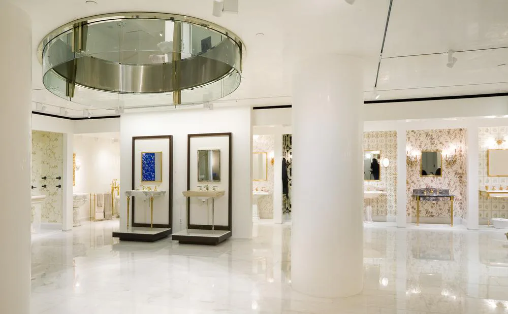Minimalist white gallery space with polished concrete floors, curved ceiling fixture, and illuminated display cases showcasing jewelry and accessories by Edward Dew Architect.