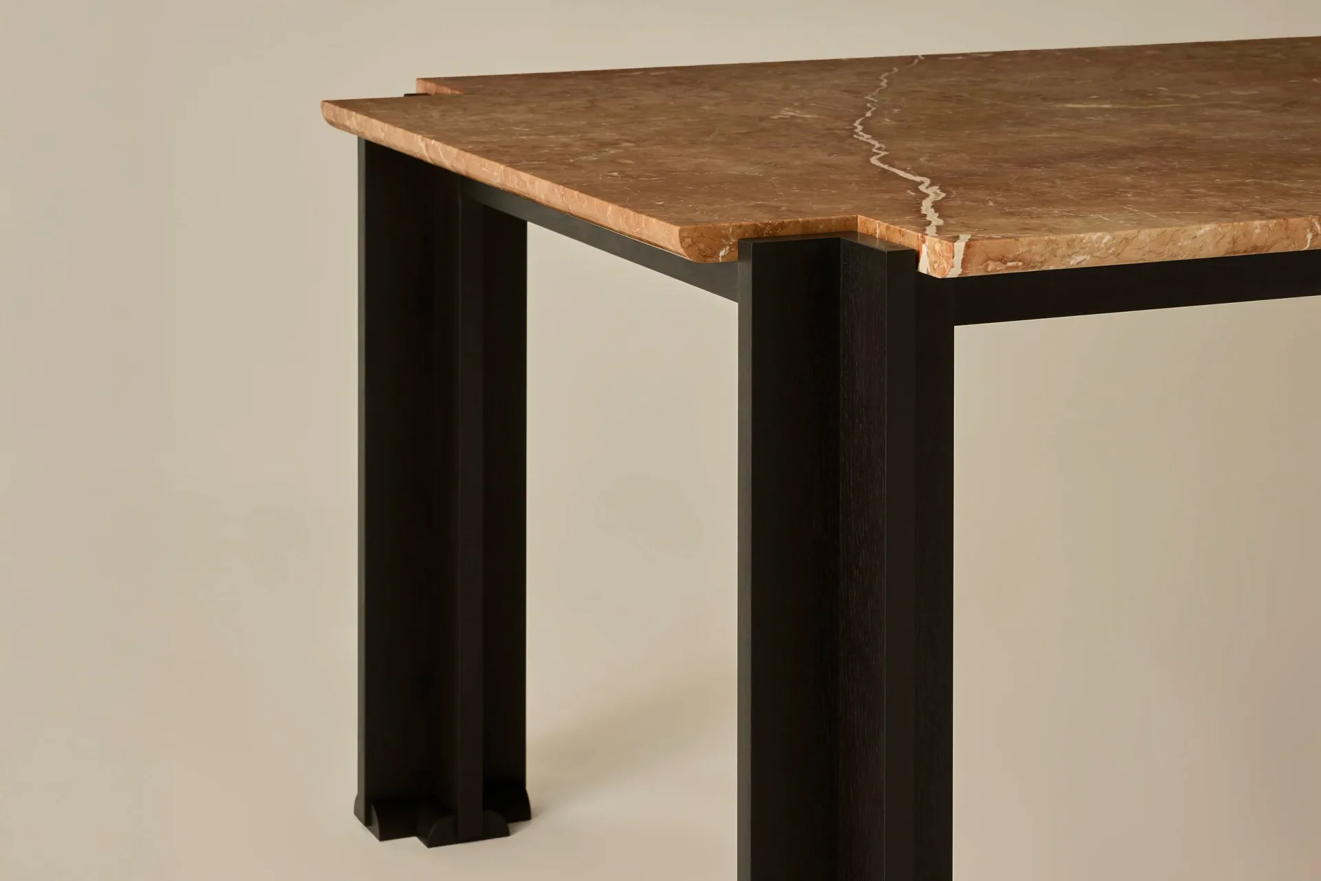 Modern dining table with live-edge wood top in warm brown tones and black metal cylindrical legs, showcasing contemporary furniture design by Egg Collective.