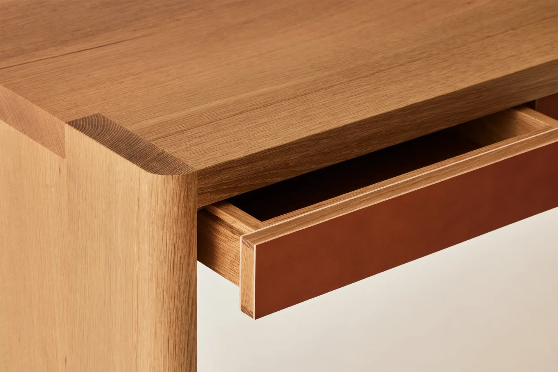 Close-up detail of a wooden desk drawer with leather front panel and brass inlay trim, showcasing fine joinery and material craftsmanship by Egg Collective.