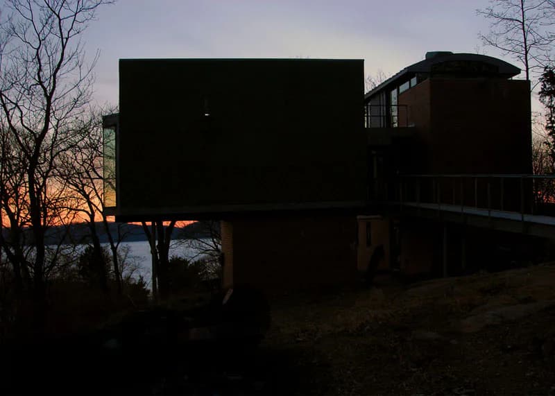 Modern residential architecture silhouetted at dusk, featuring geometric black forms with clean lines overlooking water, designed by Elemental Architecture LLC.