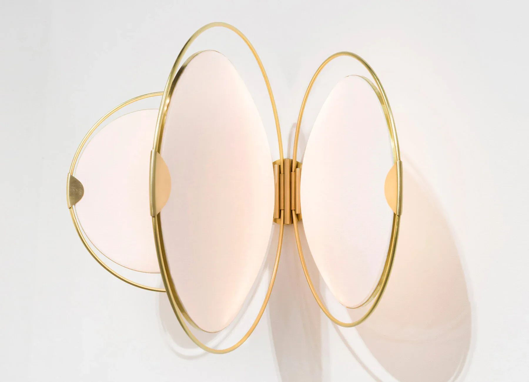 Three circular brass-framed mirrors with frosted glass panels arranged in an overlapping composition against a white wall by Elish Warlop Design Studio.