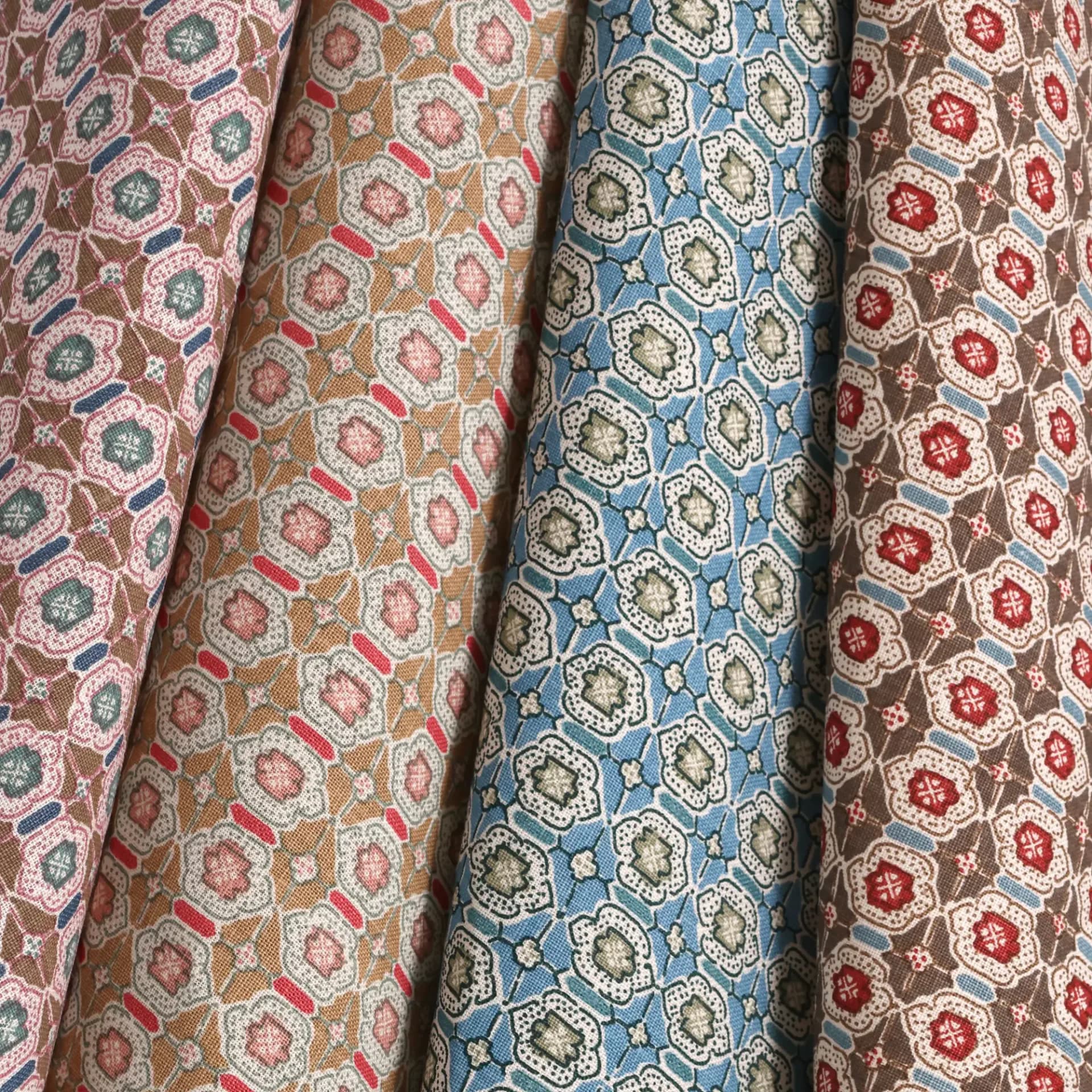 Four bolts of patterned fabric in jewel tones and neutrals displaying geometric and floral motifs by Elizabeth Eakins.