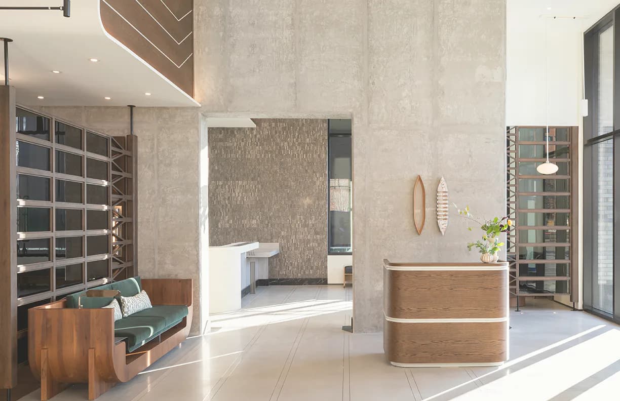 Modern spa or wellness reception area with concrete walls, wooden accents, and natural light by Ember Studio.