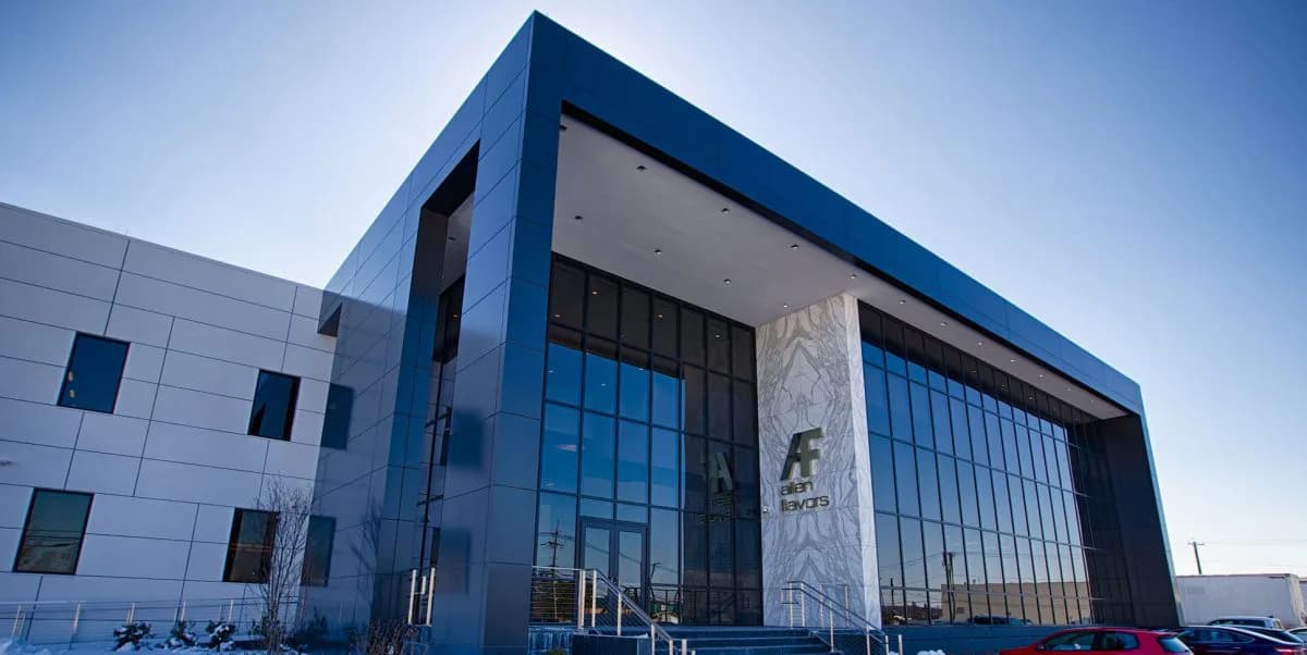 Modern institutional building with bold blue framing, extensive glazing, and white panel cladding against clear sky, designed by ENV - New Jersey.