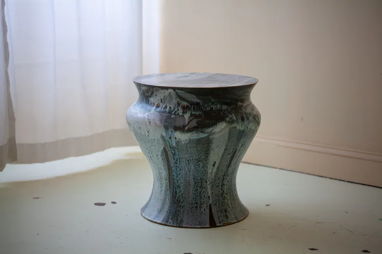 Ceramic vessel with textured glaze in muted green and gray tones, featuring a bulbous form with vertical ribbing, displayed on white surface by Episode.