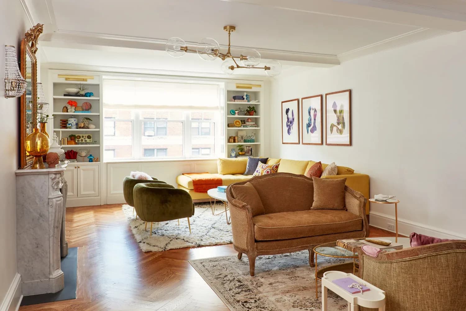 Bright living room with caramel leather sofa, mustard accent chair, built-in shelving, hardwood floors, and layered area rugs by Allison Garcy Interiors.