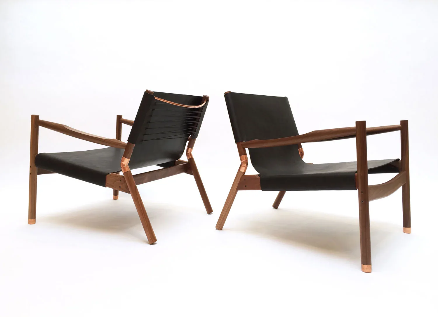 Two modernist lounge chairs with wooden frames and black leather slings positioned against a white background, showcasing minimalist seating design by Erickson Æsthetics.