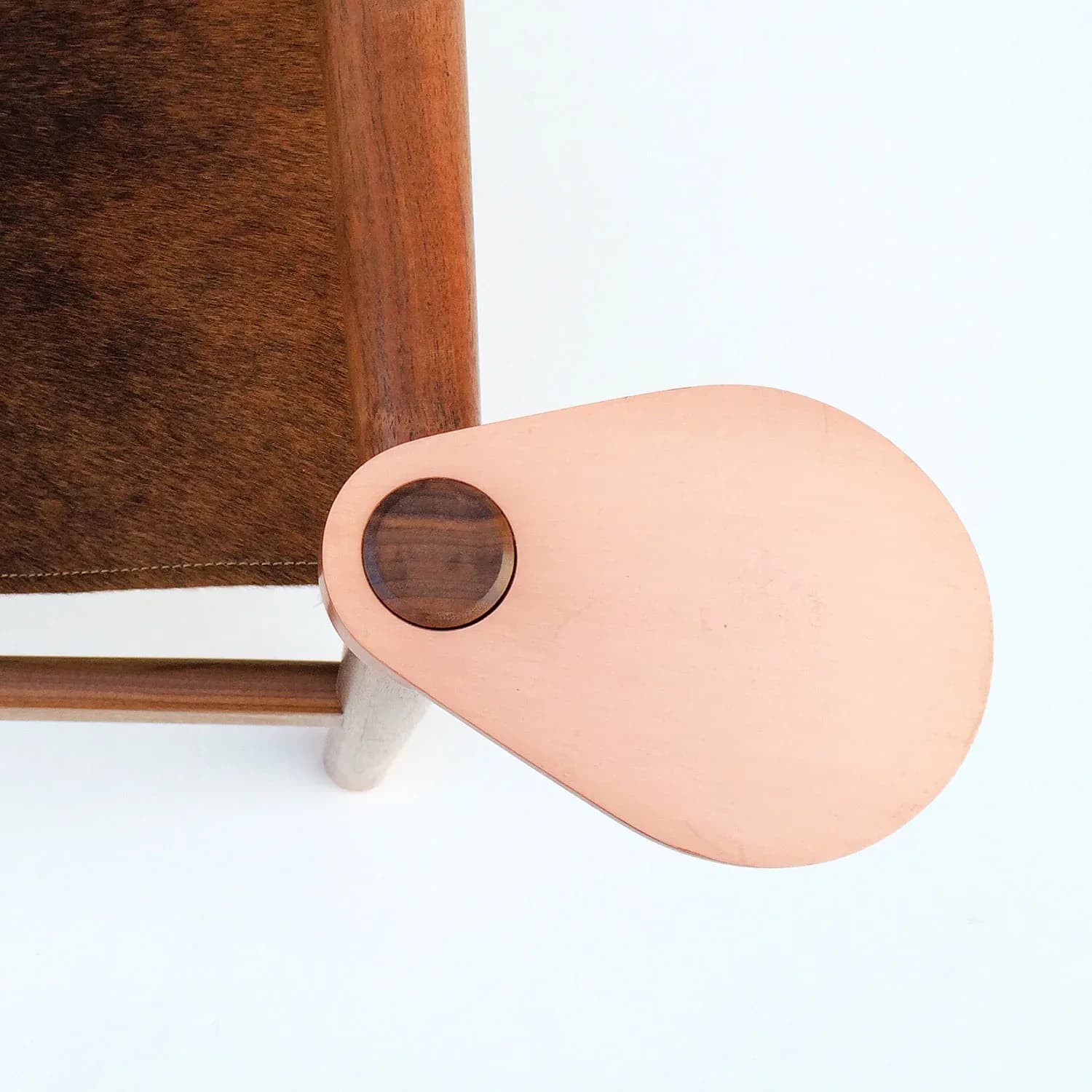 Minimalist leather accessory featuring a peach-toned teardrop-shaped form with circular aperture, paired with cognac-brown leather, by Erickson Æsthetics.
