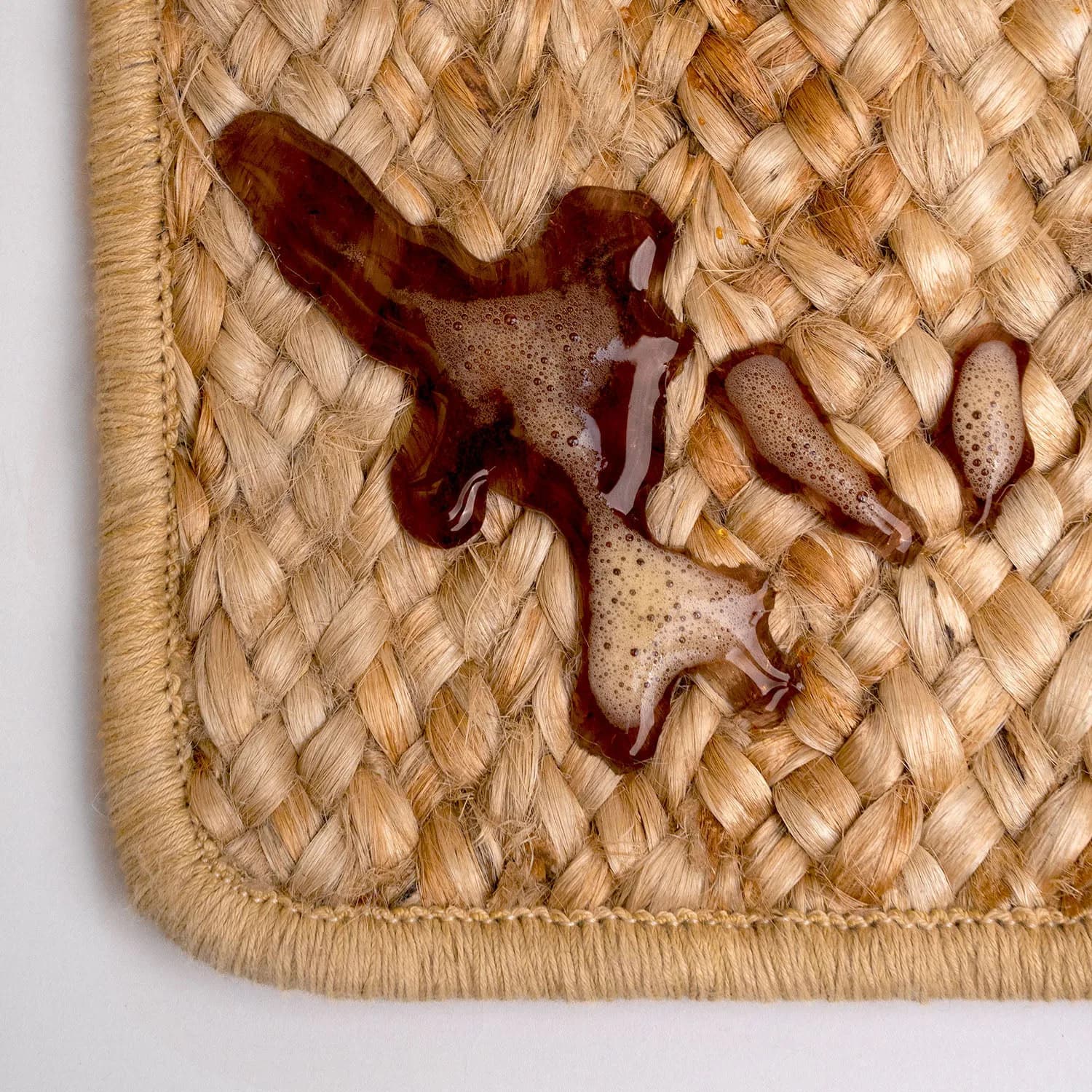 Natural woven straw placemat or table surface with deep burgundy octopus design by Ernesta.