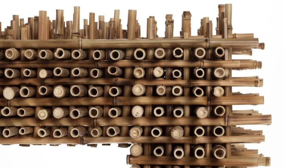 Wooden architectural installation featuring stacked cylindrical tubes and a skyline silhouette in natural wood tones by Estudio Campana.