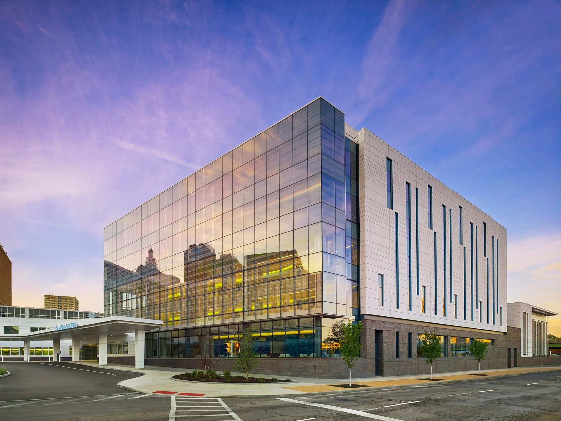 Modern institutional building with glass and stone facade, featuring yellow-green accent panels and vertical striations, photographed at dusk by EwingCole.