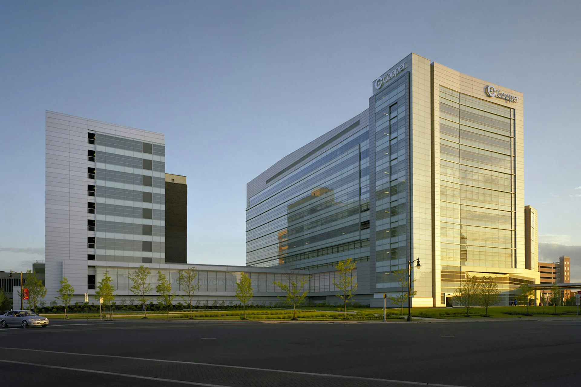Modern office campus with illuminated glass and metal facades at dusk, featuring three connected buildings with clean lines and contemporary materials by EwingCole.