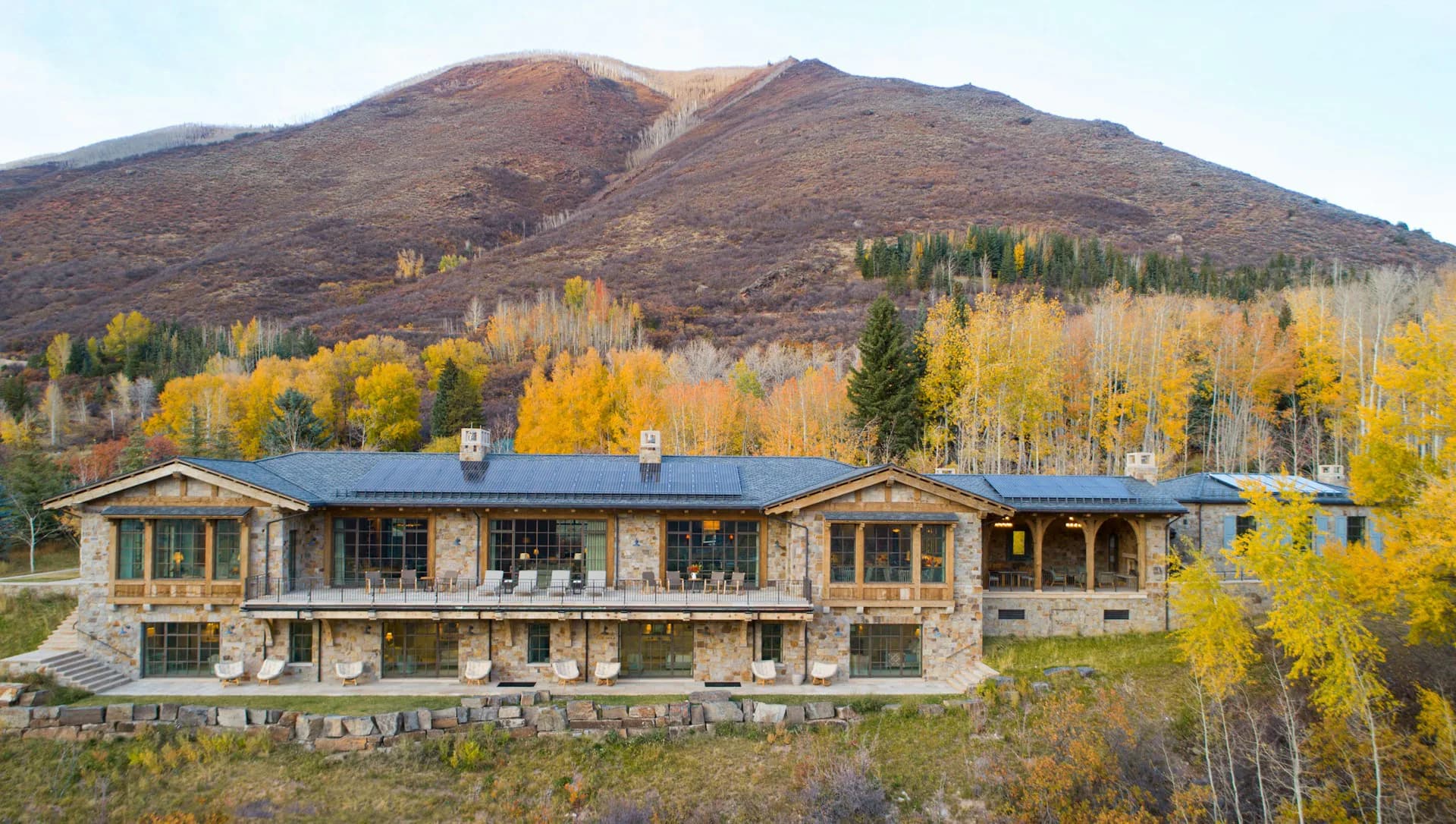 Modern residential mountain home with stone and wood façade nestled among golden aspens and evergreens by Ferguson & Shamamian Architects.
