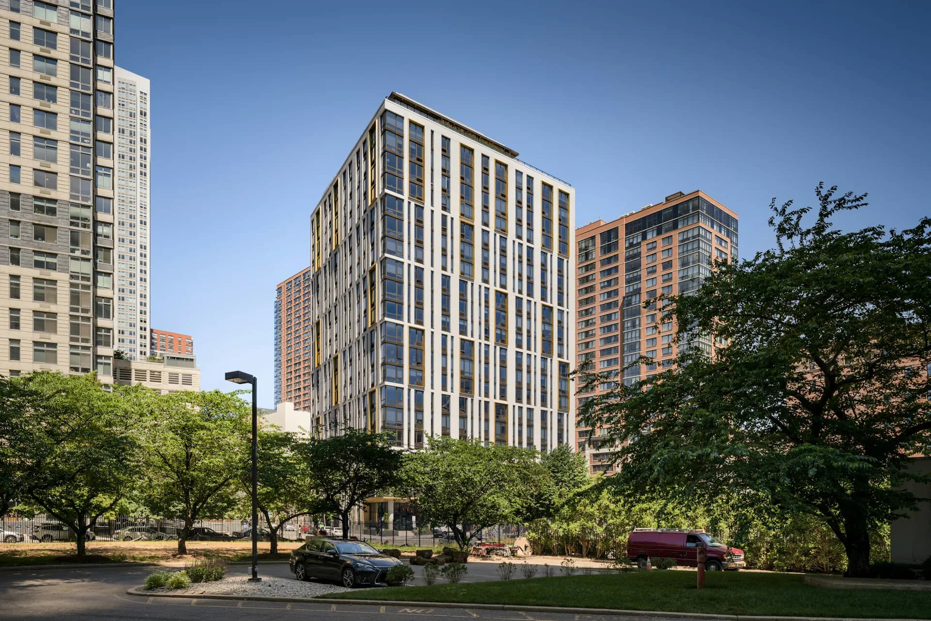 Modern residential building with vertical striping and glass facade set among trees and older adjacent structures in an urban setting by Fogarty Finger.