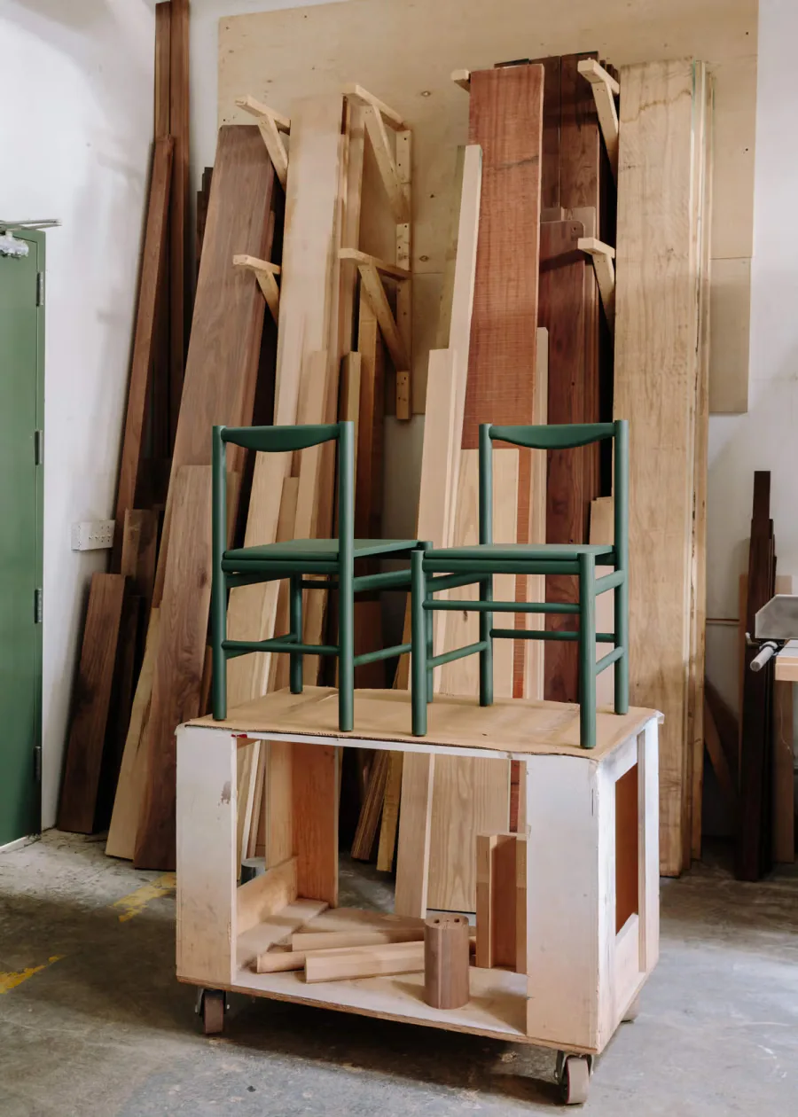Wooden furniture installation featuring stacked timber boards, green chairs, and a storage base structure in a workshop setting by Fort Standard.