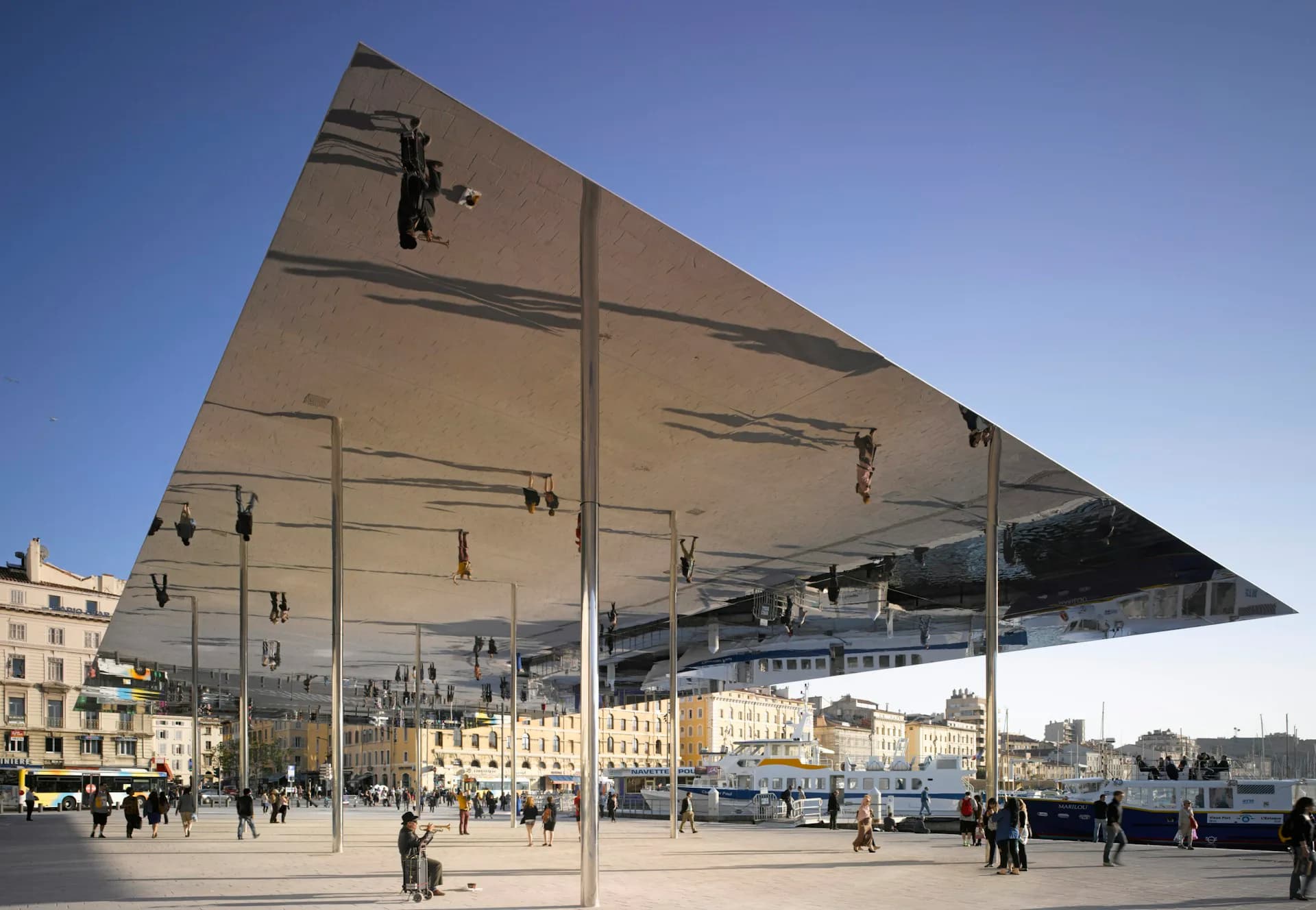 Mirrored canopy structure with geometric triangular design reflecting cityscape and plaza with pedestrians below, by Foster + Partners.