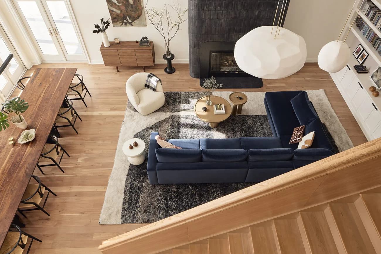 Open-plan living space with navy sofa, wooden dining table, and natural light from clerestory windows, designed by Frederick Tang Architecture.