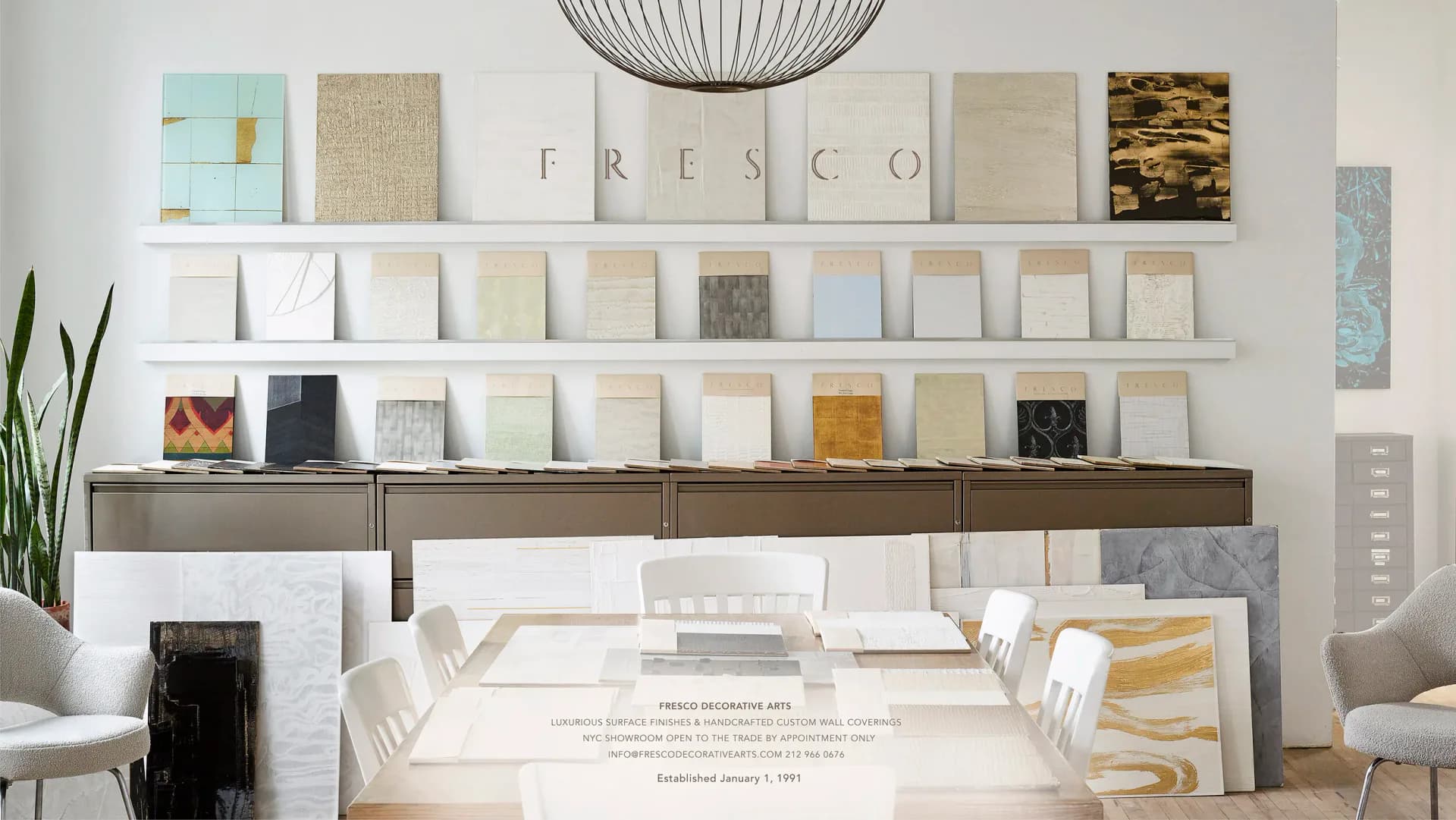 Showroom display with white shelving featuring paint samples, fabric swatches, and decorative materials in neutral tones, curated by Fresco Decorative Arts.