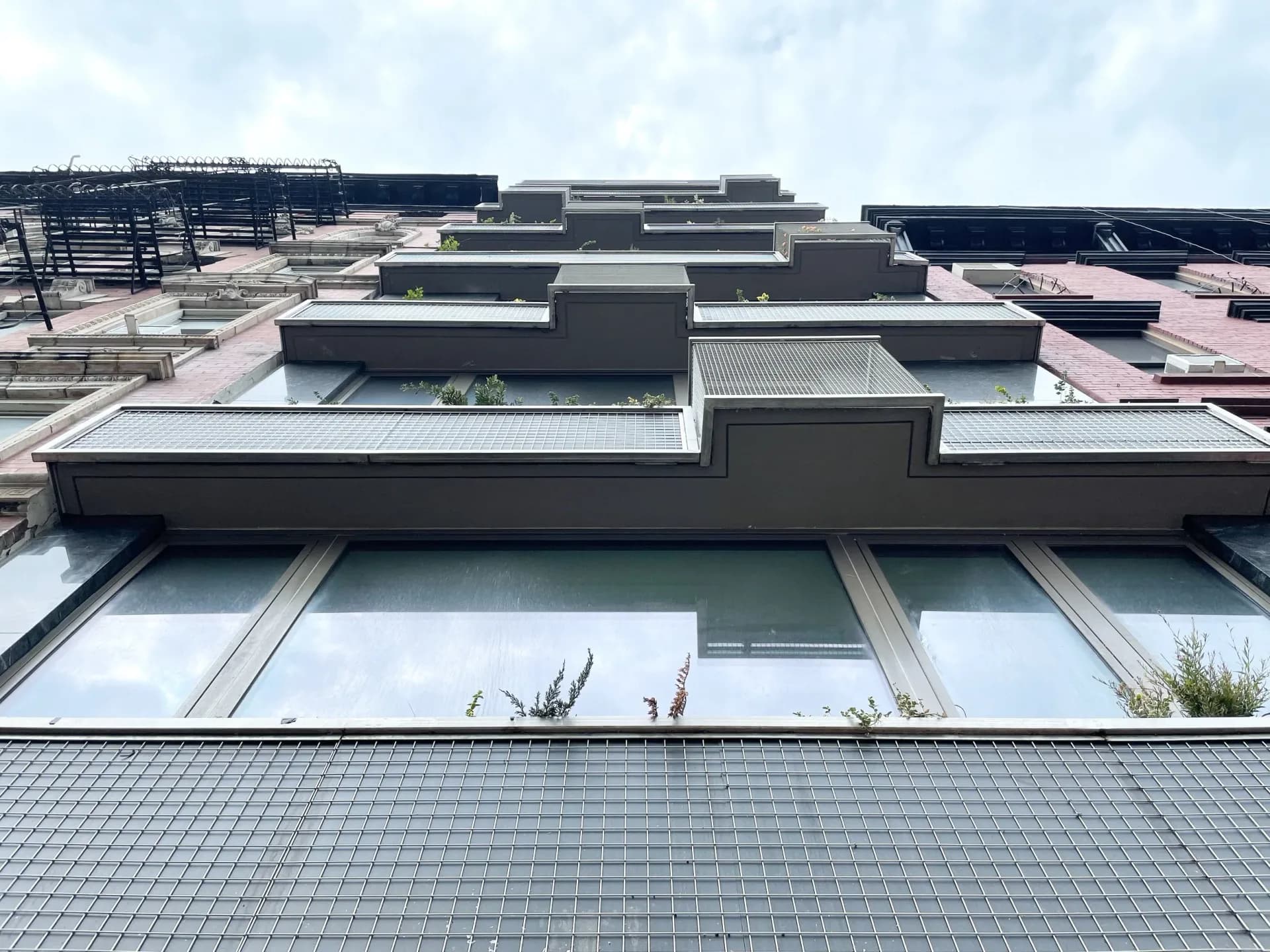 Contemporary residential building facade with stacked dark and light volumes, large windows, and green roof terraces, designed by Freyer Collaborative Architects.