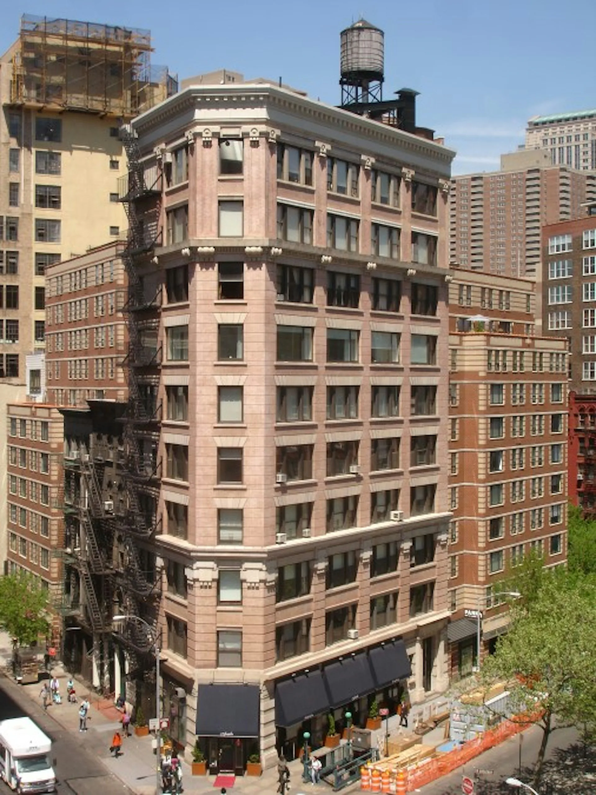 Pink and brick historic corner building with classical architectural details and street-level retail, photographed in an urban setting by FSI Architecture PC.