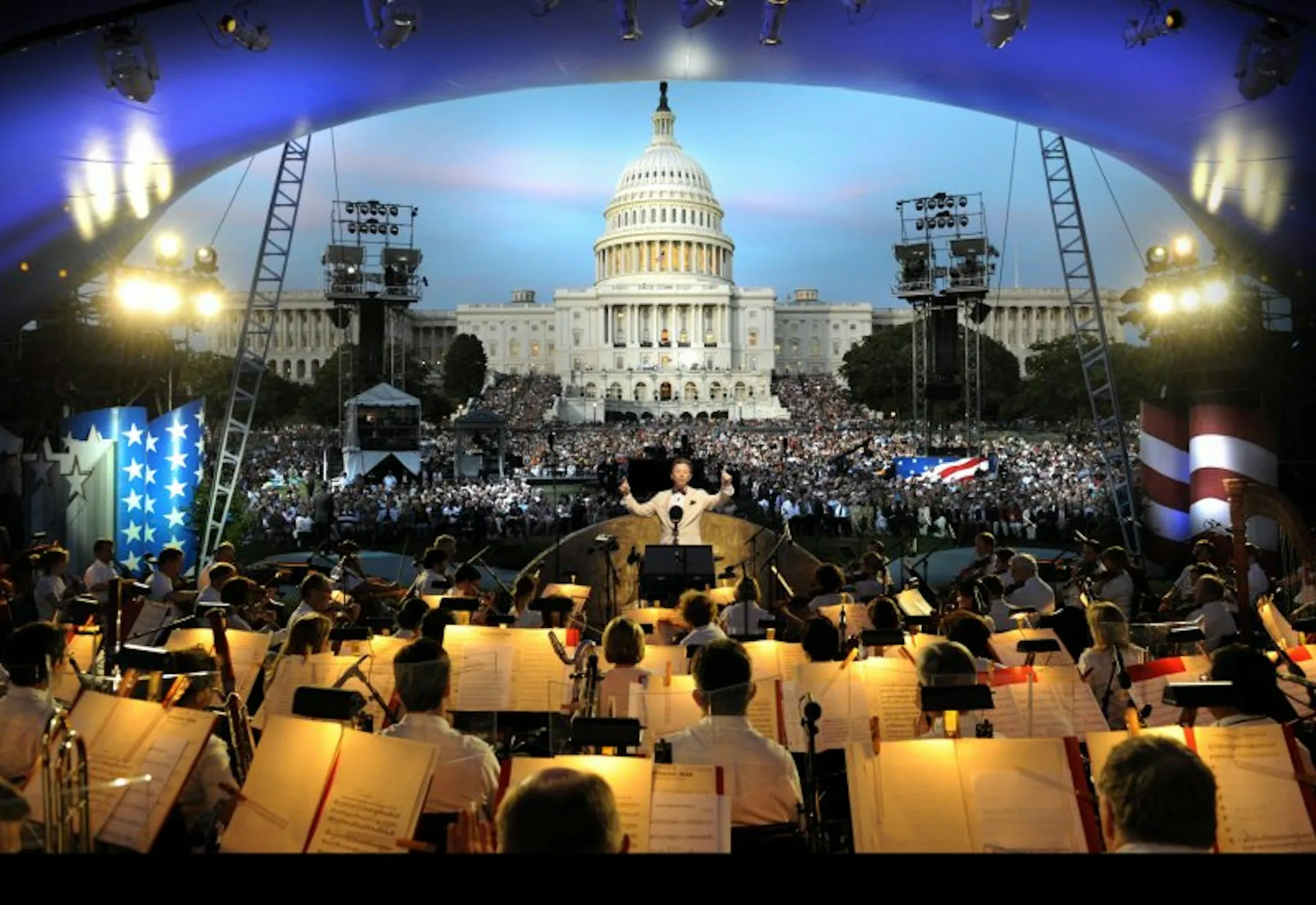 Large-scale outdoor event installation featuring orchestra seating facing the U.S. Capitol building with dramatic curved screen overhead and professional stage lighting by FTL DESIGN ENGINEERING STUDIO.