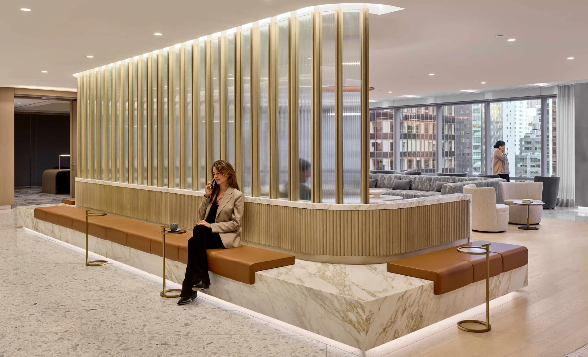 Modern reception desk with vertical wood slat screening, marble base, and wooden bench seating overlooking a city skyline, designed by FXCollaborative.