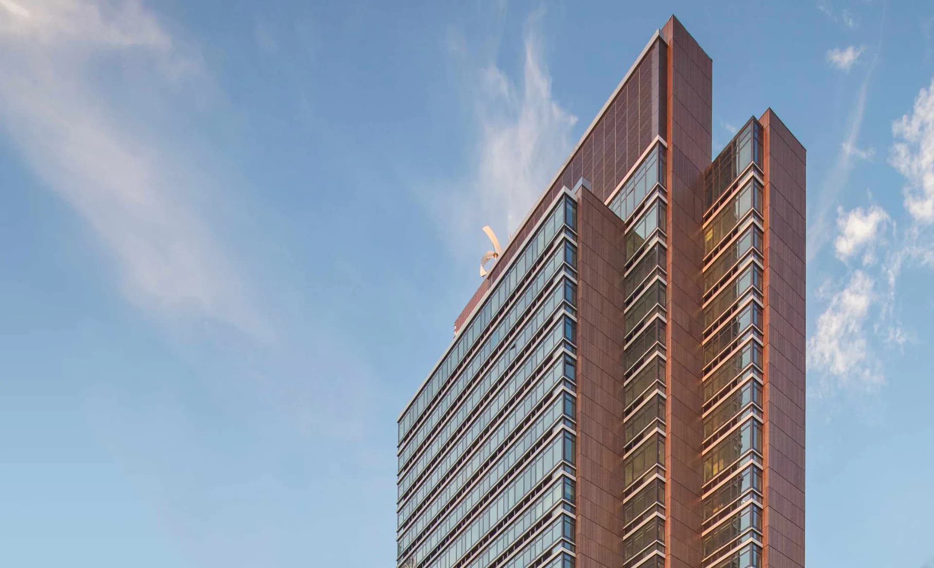 A tall residential tower with brick and glass facade featuring prominent vertical lines and setbacks, designed by FXCollaborative.