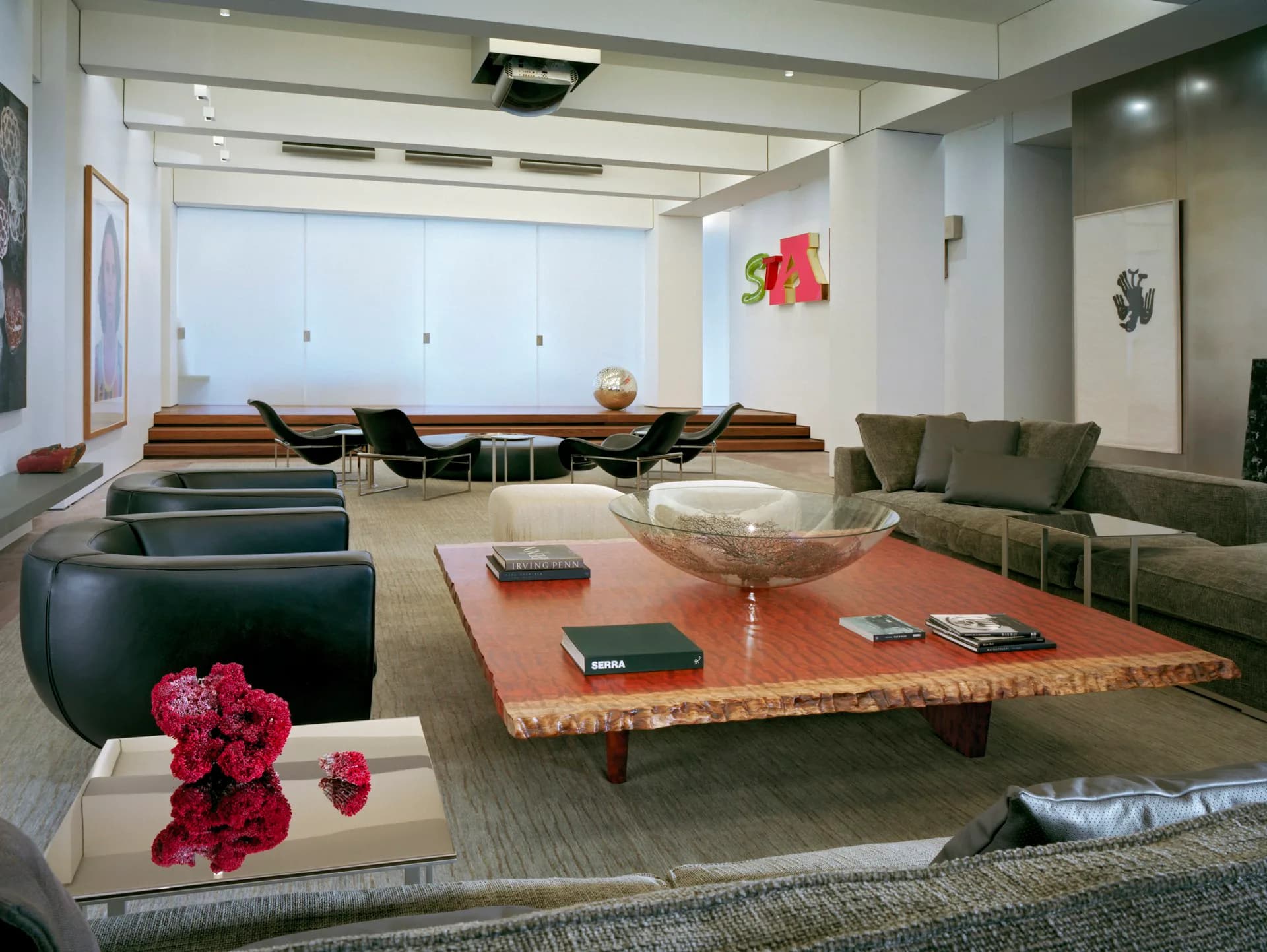 Modern lounge space with low-slung seating, natural wood coffee table, olive-green upholstery, and floor-to-ceiling windows, designed by Gabellini Sheppard Associates.