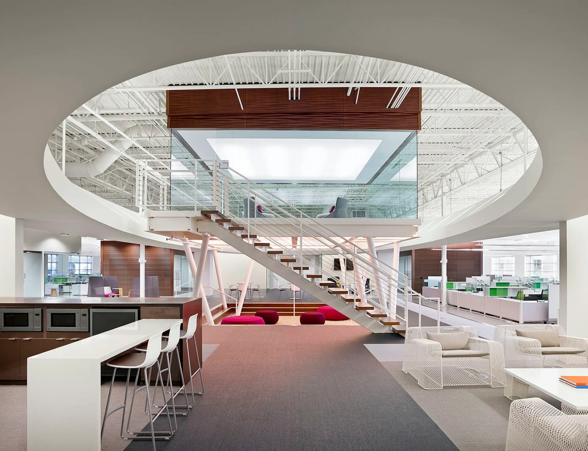 Architectural rendering of a modern interior with circular ceiling, mezzanine staircase, kitchen area, and open floor plan in warm and neutral tones by Gensler.