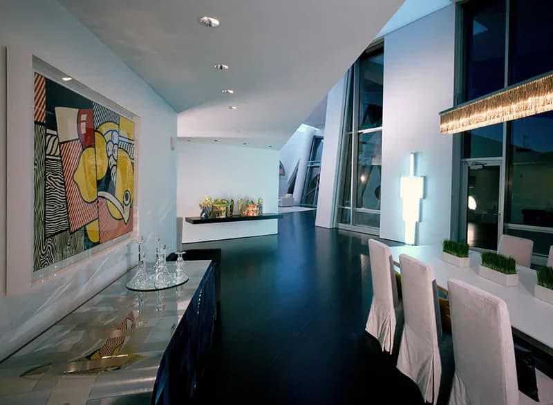 Modern bathroom with dark vanity, white towels, colorful artwork, and natural lighting by George Sexton Associates.