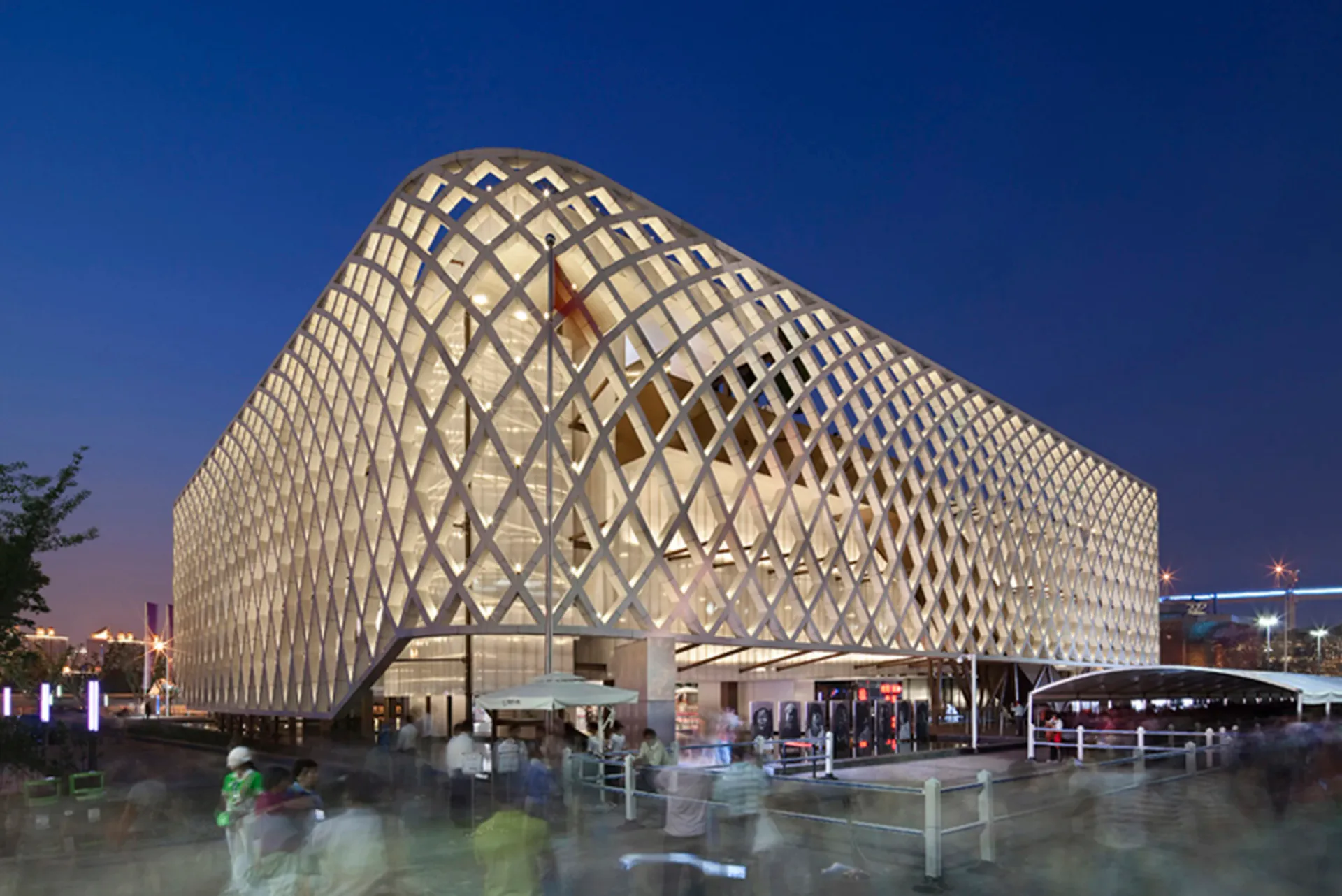 Illuminated latticed exterior of a modern institutional building at dusk, showcasing geometric facade design and landscape lighting by George Sexton Associates.