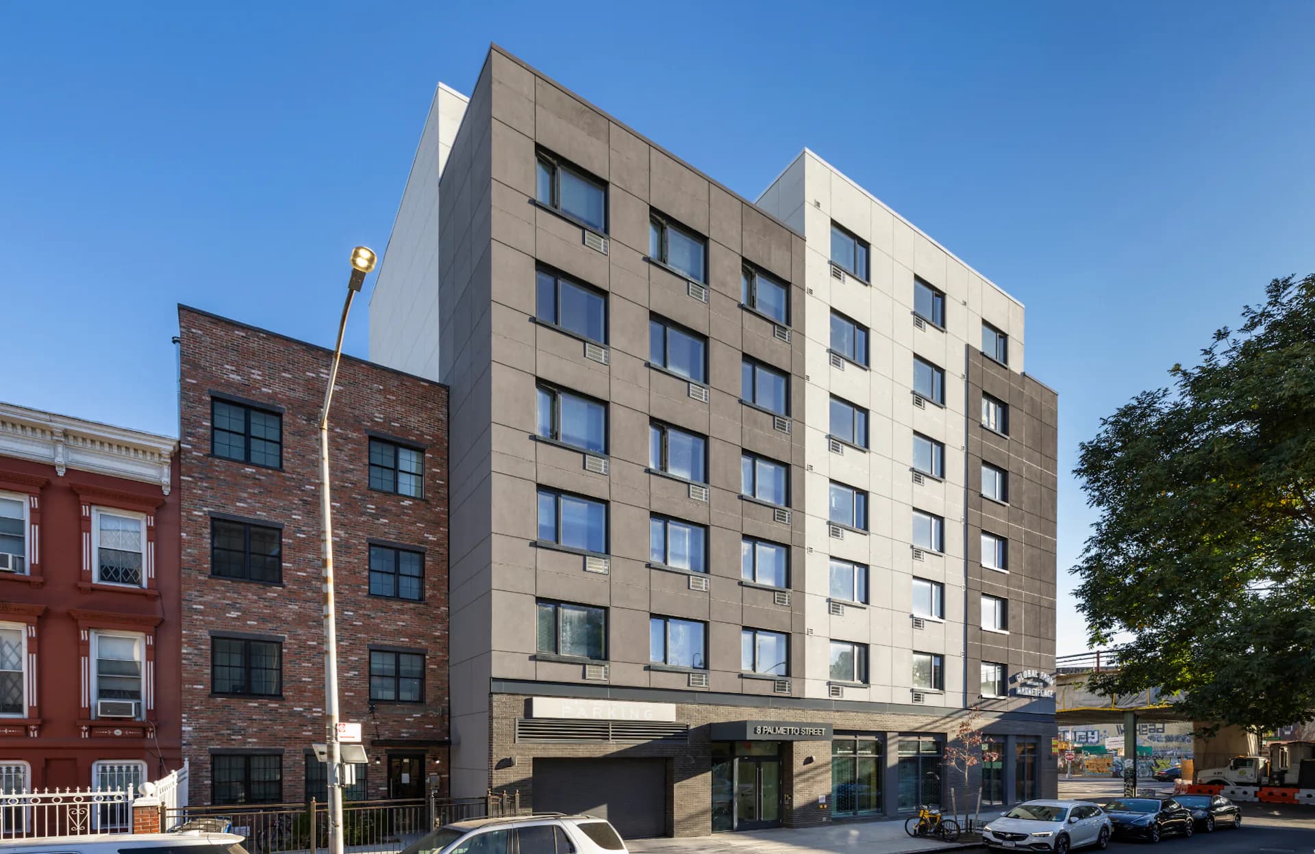 Contemporary mixed-use building with tan and dark facade, ground-floor retail, and residential units above, designed by GF55 Architects.