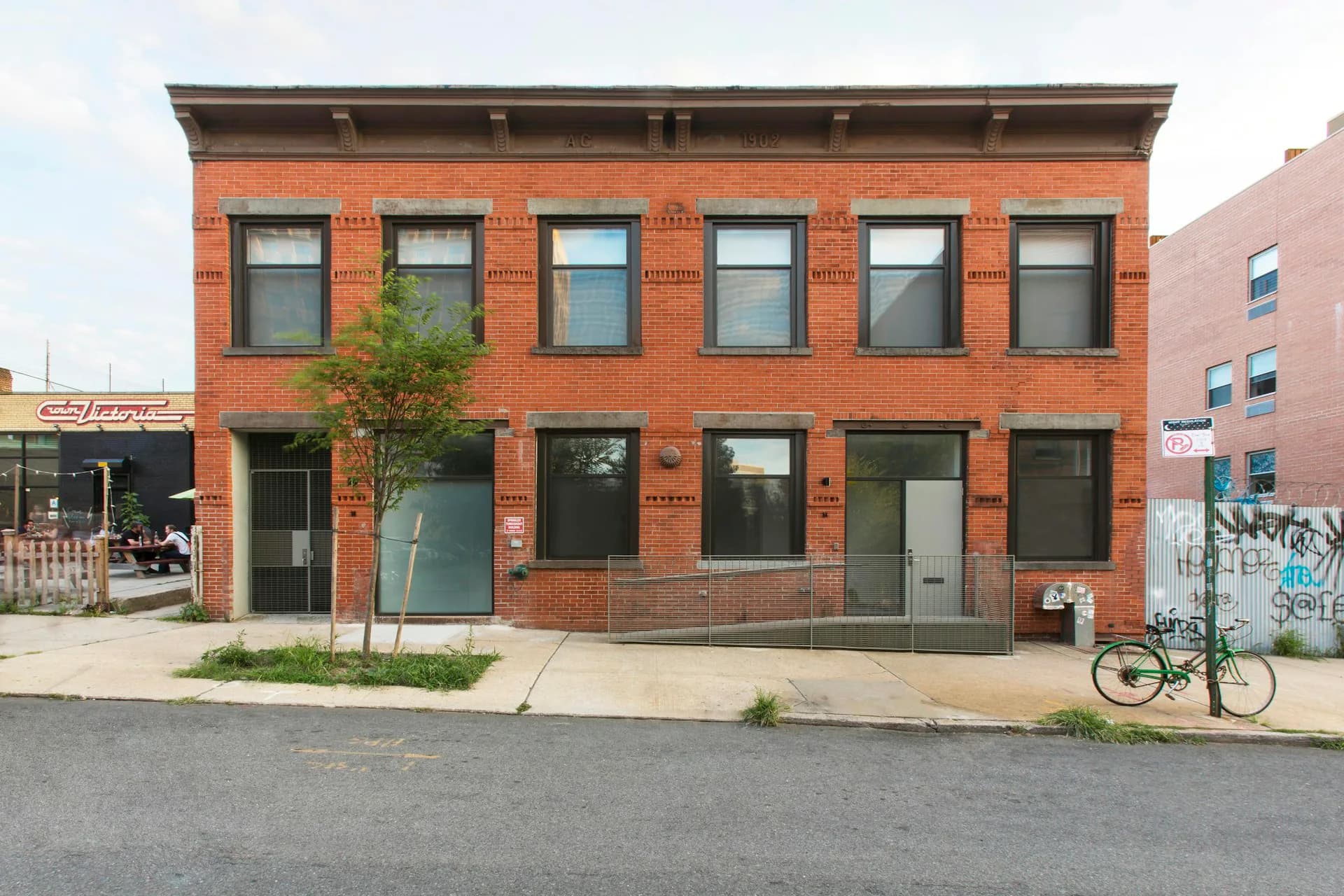Exterior facade of a contemporary red brick mixed-use building with symmetrical window arrangement and ground-level retail spaces, designed by Glickman Schlesinger Architects.