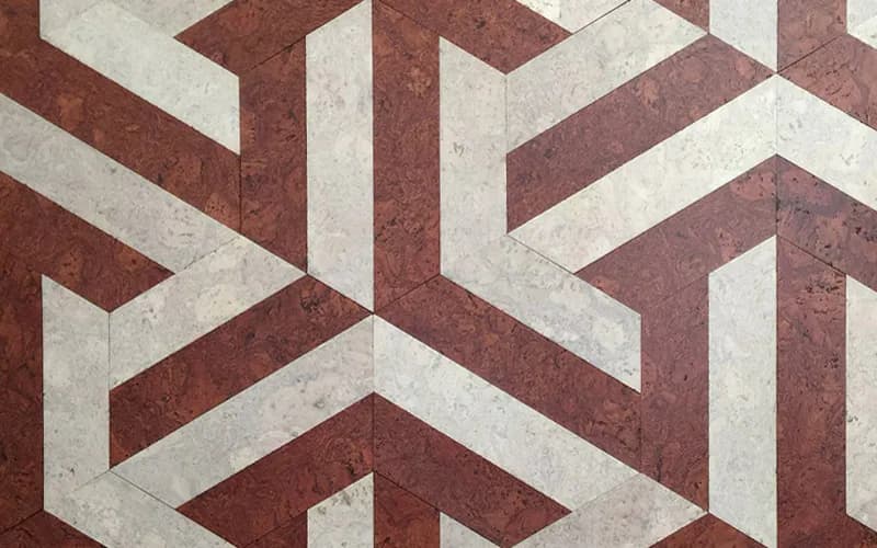 Geometric floor pattern with interlocking chevron design in deep red and cream tones, creating a modern tessellating visual effect by Globus Cork.
